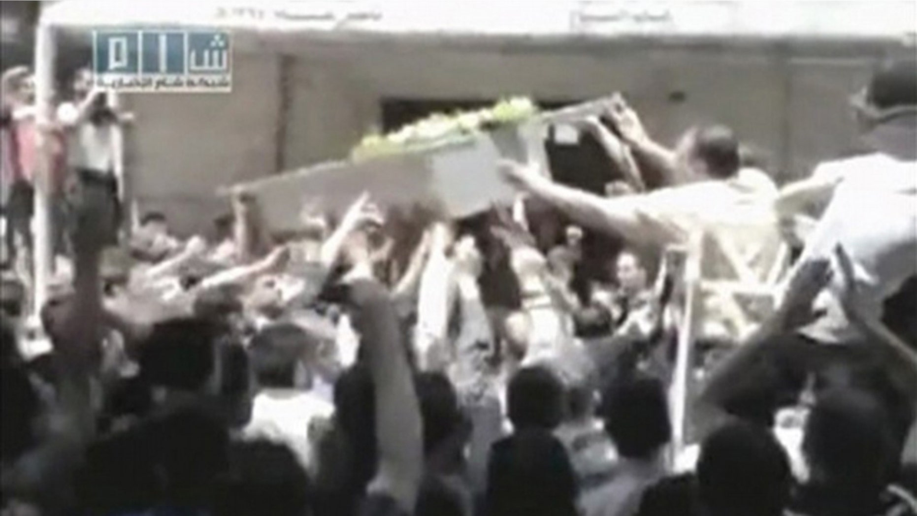 People shout slogans as a coffin is lifted onto a vehicle during a funeral for what was believed to be a person killed in the latest crackdown on protests in the city of Homs. This still image was taken from video uploaded on a social media website May 21, 2011.