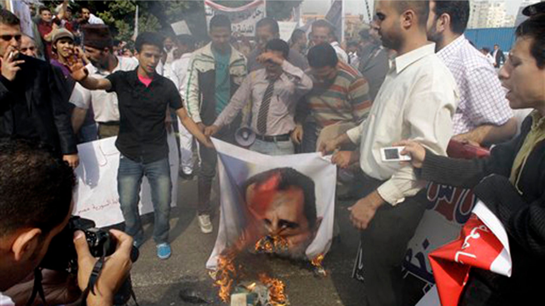 Syrian protesters burn a picture of Syrian President Bashar Assad during a protest in front of the Arab League headquarters in Cairo, Egypt, Saturday, Nov.12, 2011.