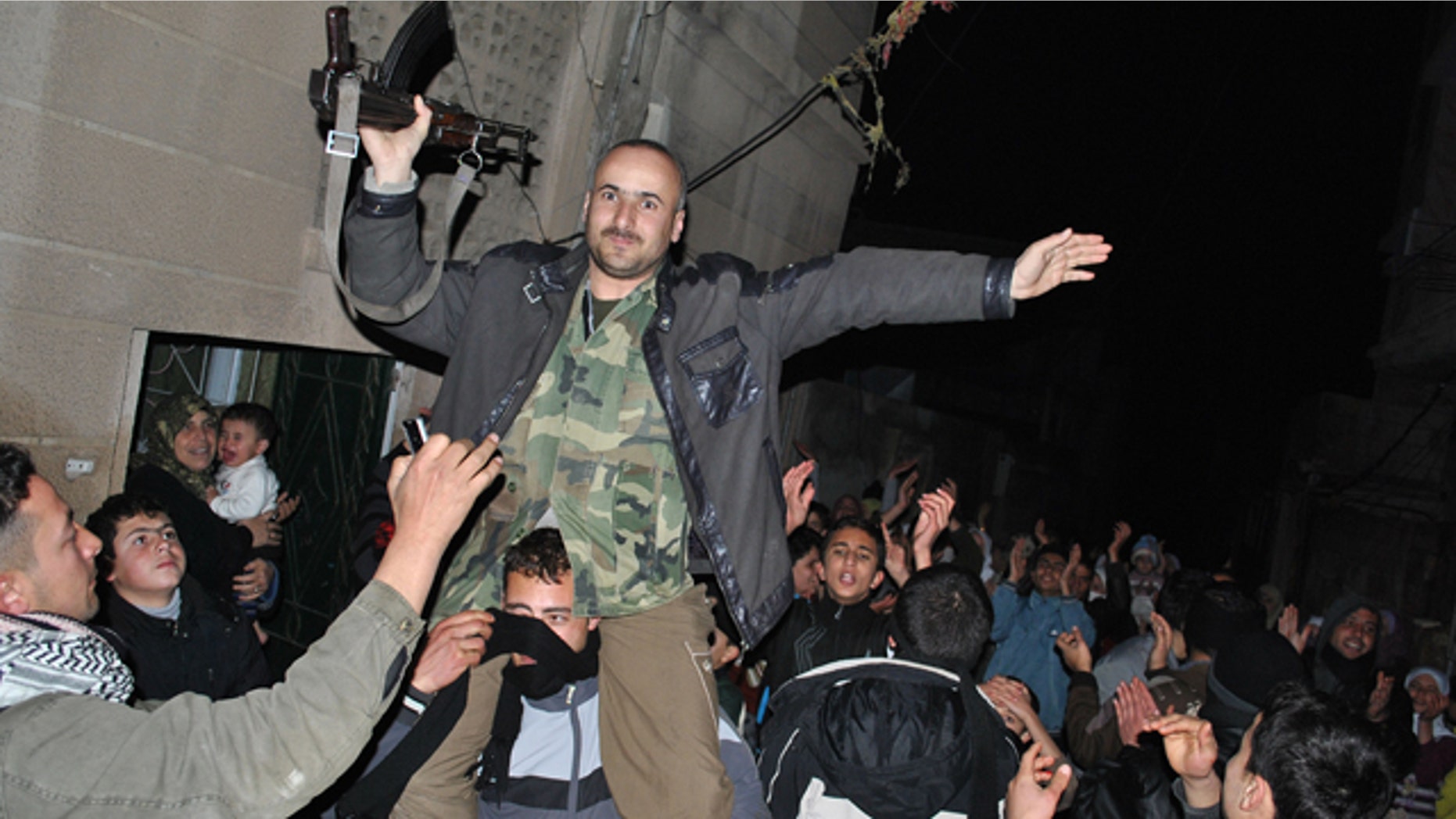 Anti-Syrian regime protesters, hold up a Syrian army defector as they chant slogans against Syrian President Bashar Assad during an evening protest, in the Rastan area in Homs province, central Syria, on Monday Jan. 30, 2012. Syrian forces heavily shelled the restive city of Homs on Monday, and troops pushed back dissident troops from some suburbs on the outskirts of Damascus in an offensive trying to regain control of the capital's eastern doorstep, activists said.(AP Photo)