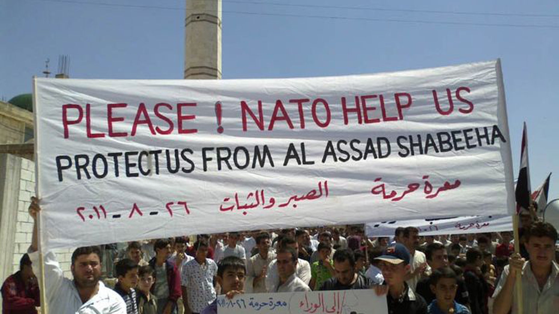 Anti-Syrian President Bashar Assad protesters, hold up a banner pleading for help from Nato, during a demonstration against the Syrian regime, at Maaret Harma village, in Edlib province, Syria, on Friday Aug. 26, 2011.