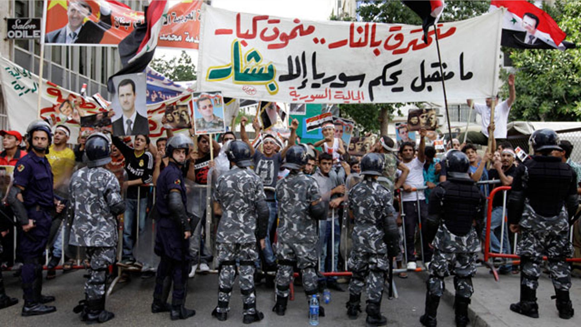 Oct. 23, 2011: Lebanese riot police officers stand guard between supporters and opponents of Syrian President Bashar Assad's regime, during a protest in front of the Syrian embassy, in Beirut, Lebanon.