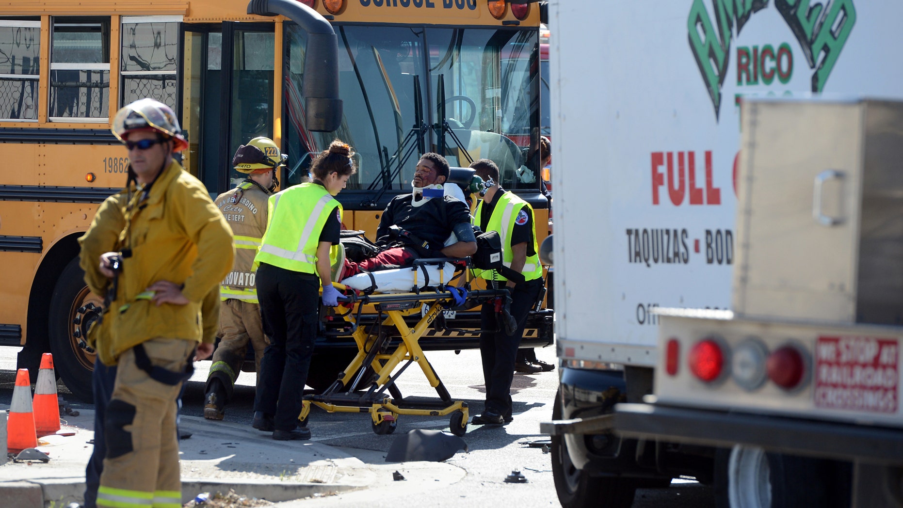 A man is transported to an ambulance at the scene of an accident involing a stolen taco truck and a school bus.
