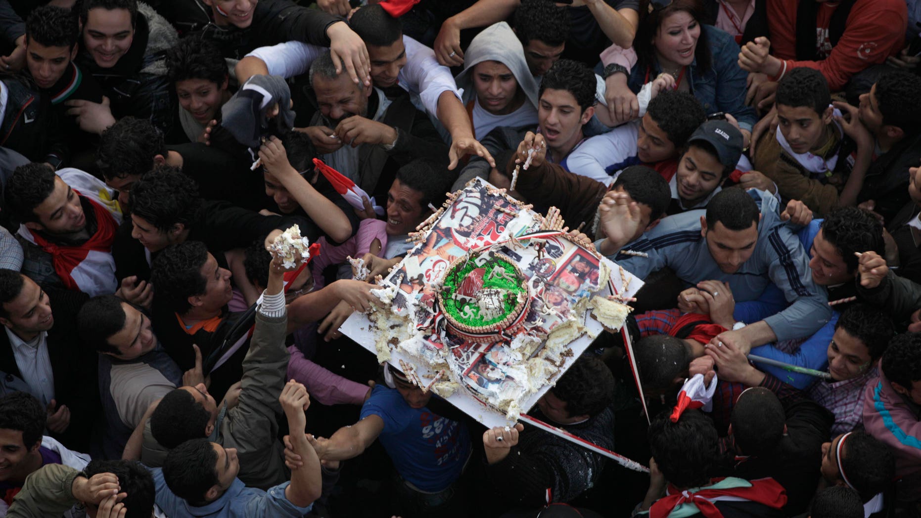 Demonstrators grab pieces of a cake as it is passed above their heads during a rally in Tahrir Square in Cairo, Egypt, Friday Feb. 18, 2011. Some thousands of flag-waving Egyptians packed into Tahrir Square for a day of prayer and celebration Friday to mark the fall of longtime leader Hosni Mubarak a week ago and to maintain pressure on the new military rulers to steer the country toward democratic reforms.