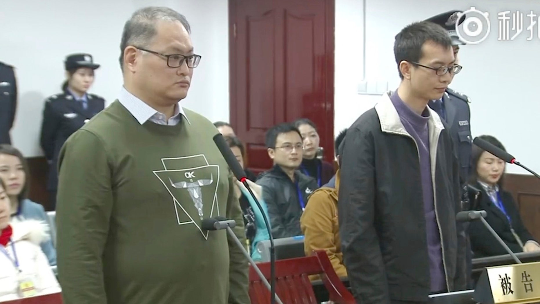 Taiwanese activist Lee Ming-che, left, and his fellow defendant Peng Yuhua of China stand at the Intermediate People's Court of Yueyang.