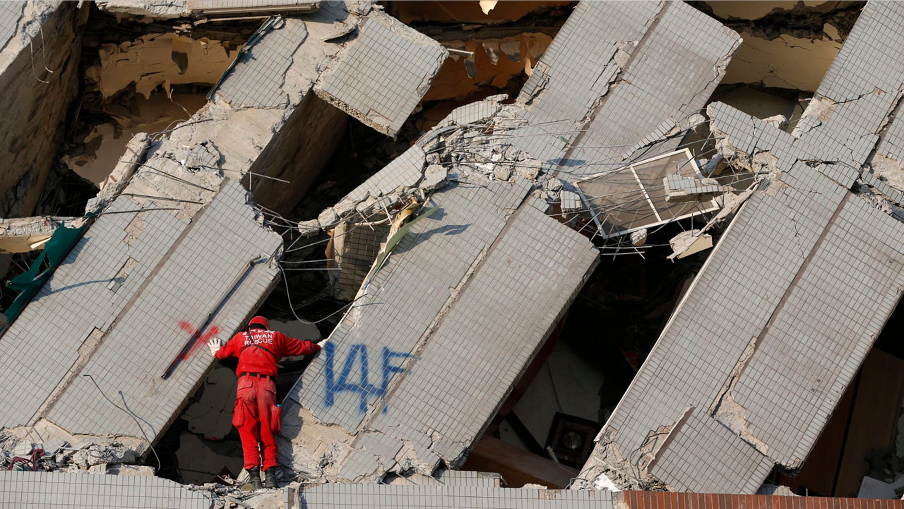 An emergency rescue worker searches what was the 14th floor of a collapsed building in Tainan, Taiwan, Sunday, Feb. 7, 2016. Rescuers on Sunday found signs of live within the remains of a high-rise residential building that collapsed in a powerful, shallow earthquake in southern Taiwan that killed over a dozen people and injured hundreds. (AP Photo/Wally Santana)