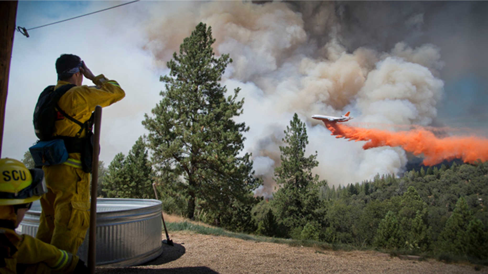 July 26, 2014: A DC-10 Air Tanker makes a drop on the Sand Fire at the middle fork of the Cosumnes River in Northern California as firefighters standby to protect a home.