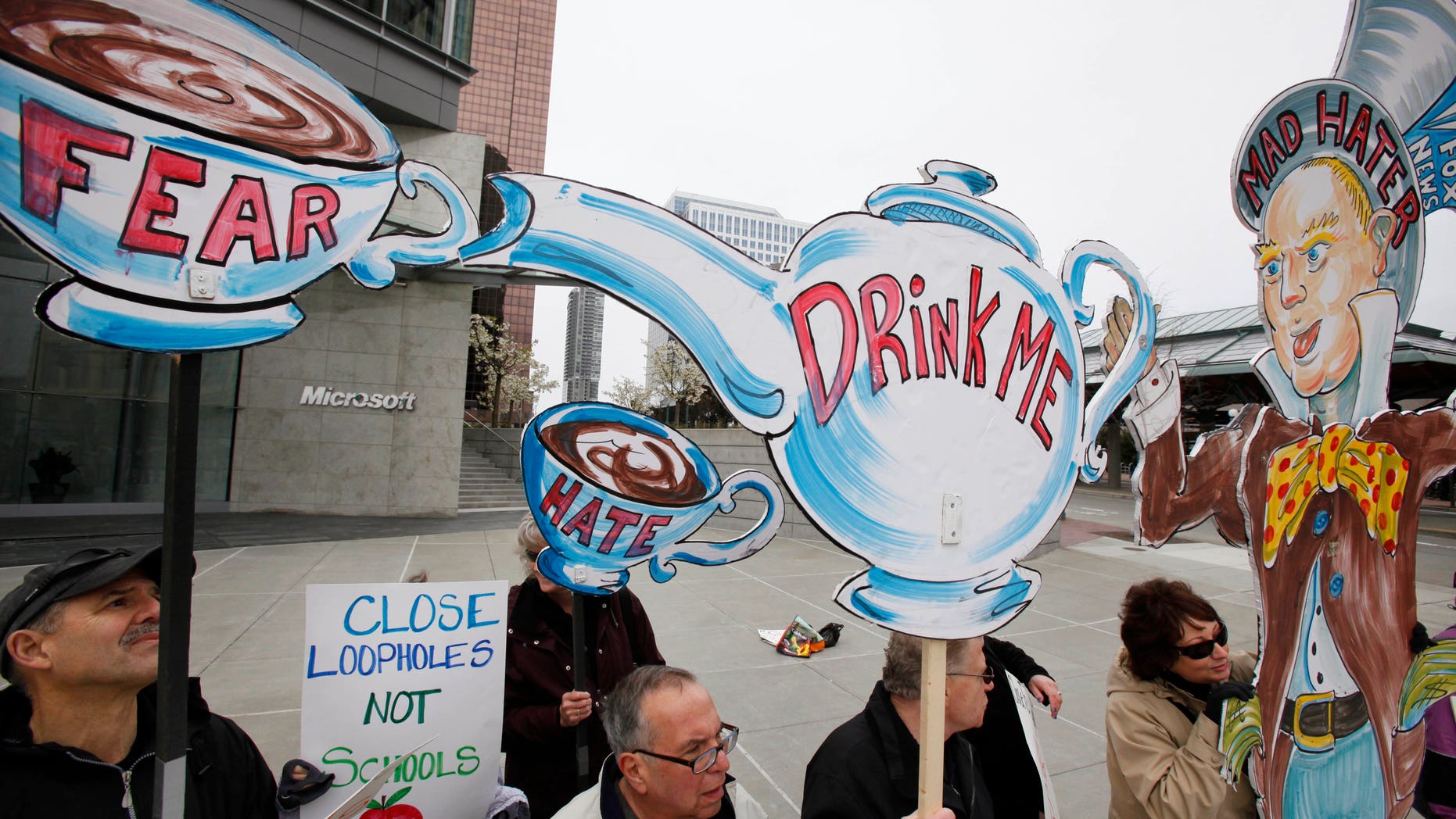Several dozen protesters using a "mad hatter" theme counter-demonstrate against a tax day tea party rally of about a hundred protesters nearby Friday, April 15, 2011, in Bellevue, Wash. (AP)