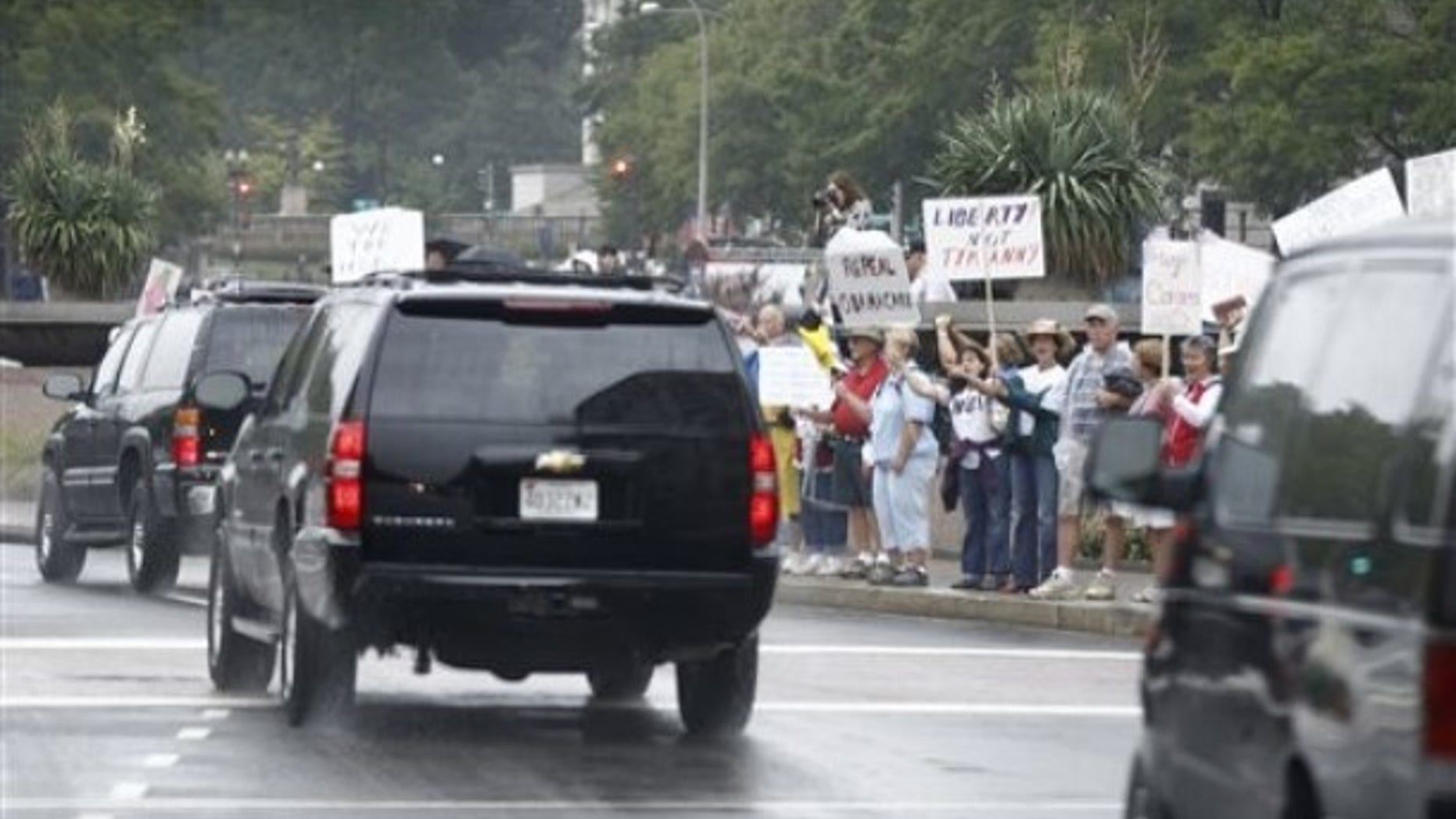 Sunday: President Obama's motorcade drives towards the White House past Tea Party protesters.