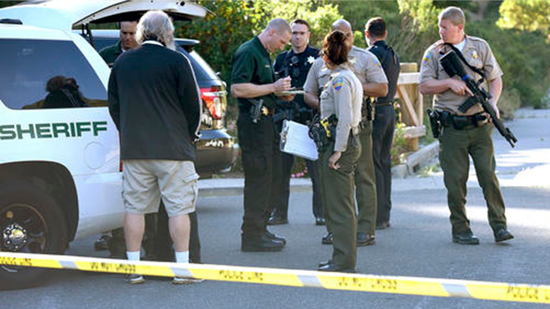 In this photo taken Wednesday, May 25, 2016, Marin County Sheriff and Novato police members gather at a command post to form a massive manhunt following at attack on two students in Novato, Calif. Attackers shot two students near a San Francisco Bay Area high school, killing one and sending another to a hospital in an incident that prompted the closing of the campus, authorities said Thursday. Both victims were students at Novato High School. (Robert Tong/Marin Independent Journal via AP)