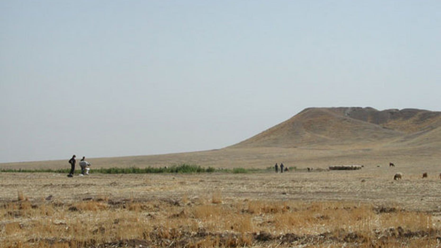 Archaeologists inspect the mound at Tell Brak, in northeastern Syria. The 283 million cubic foot (8 million cubic meter) mound is entirely artificial, accumulating over 6,000 years, as residents built on top of old mud brick buildings.