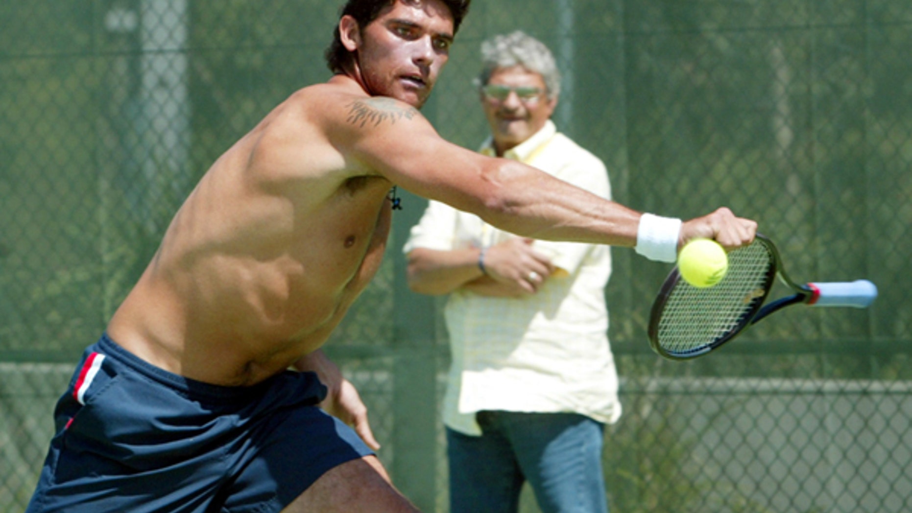 Mark Philippoussis of Australia plays at the ball with the handle of his racket as his father Nick looks on during practice at the Sydney International Tennis Center in January 2004.