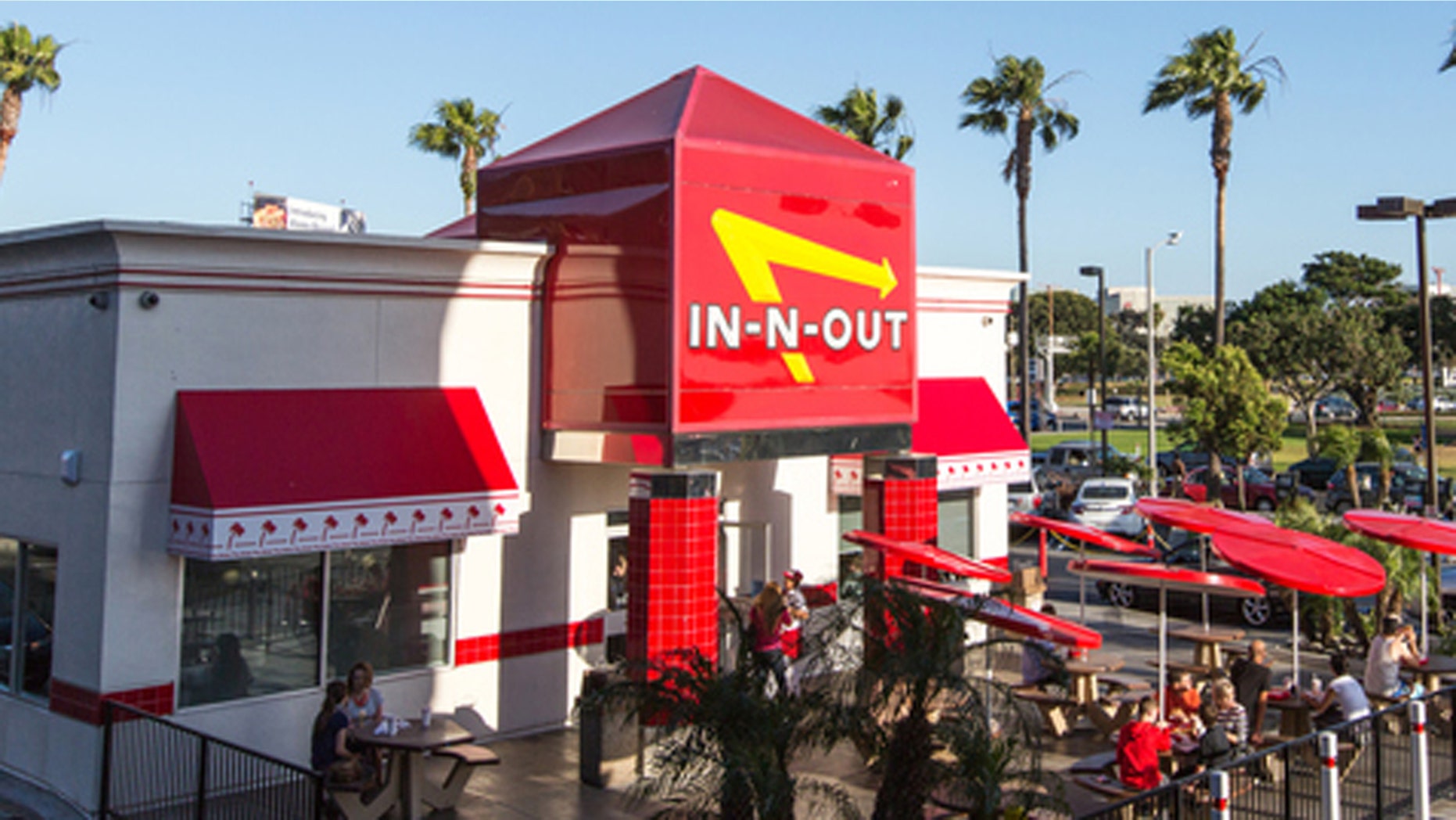 Los Angeles, USA - April 4, 2015: Airplane flying over In-n-Out Burger, LAX, few cars are leaving In-n-out parking lot. People eating outside the restaurant.