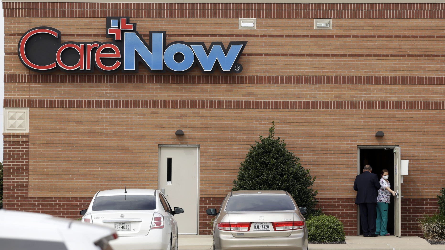 Oct. 8, 2014: A masked worker opens a door at a CareNow clinic in Frisco, Texas.