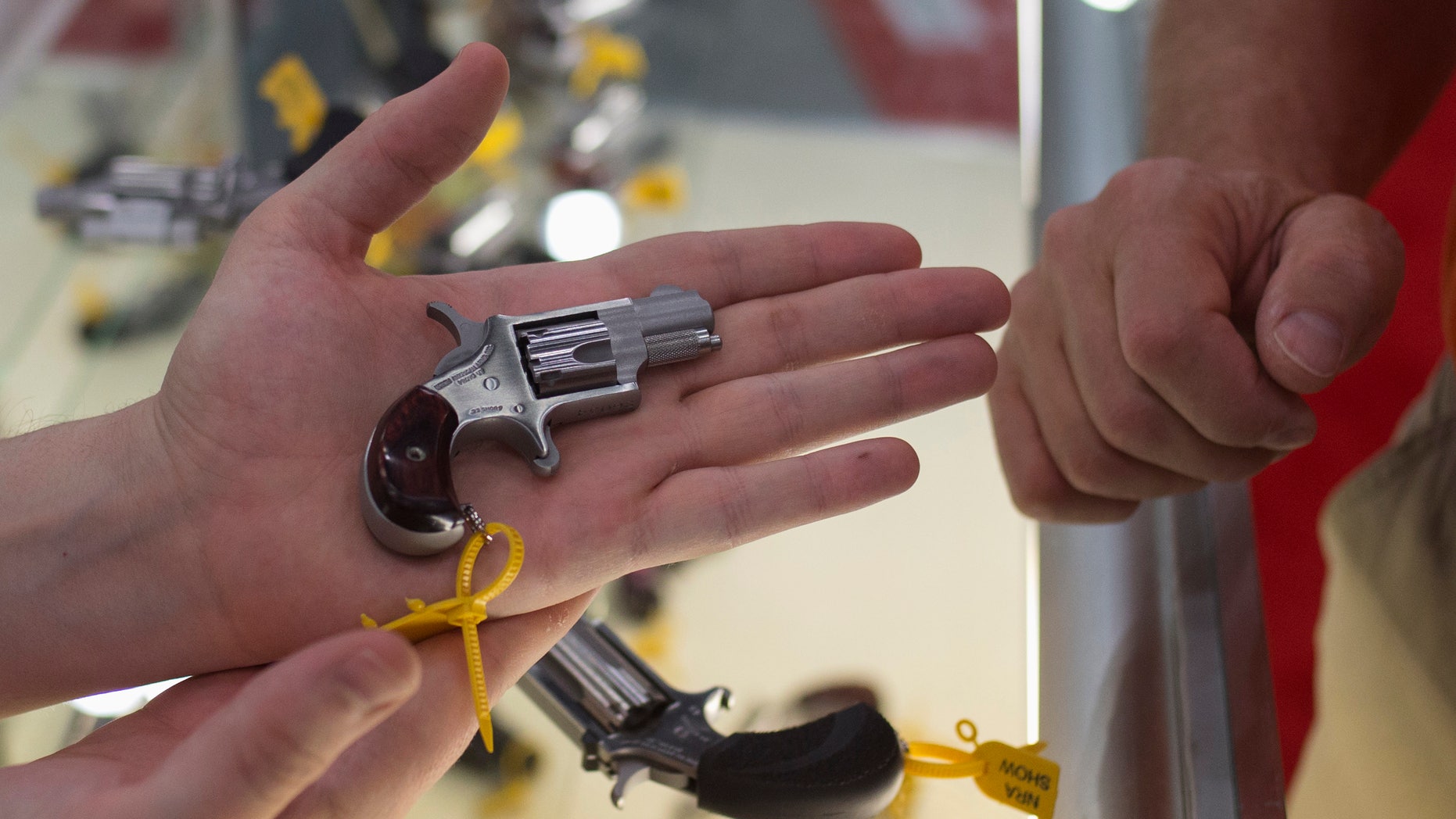 May 4, 2013: An exhibitor shows a North American Arms .22 short mini revolver to an event goer during the National Rifle Association's annual meeting in Houston, Texas.