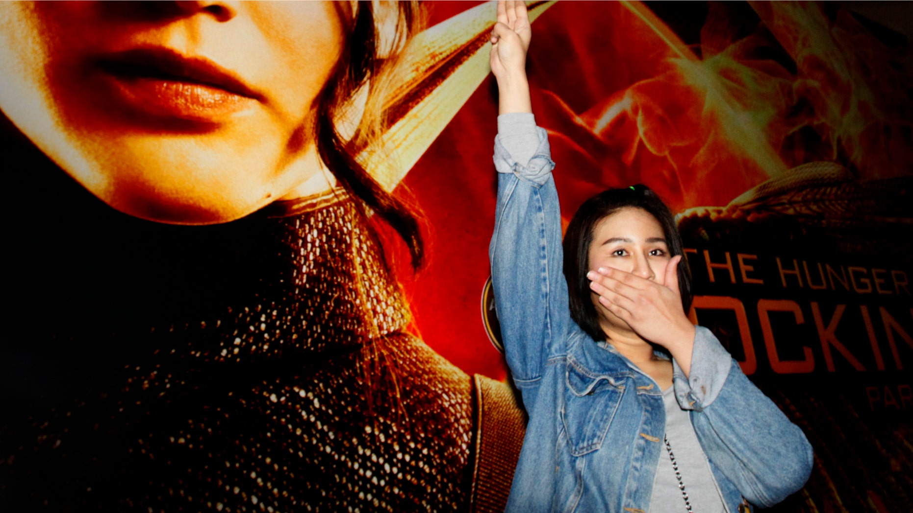 Nov. 20, 2014: Nachacha Kongudom, 21, raises a three-finger salute outside a cinema where “The Hunger Games: Mockingjay - Part 1” is showing, in Bangkok, Thailand