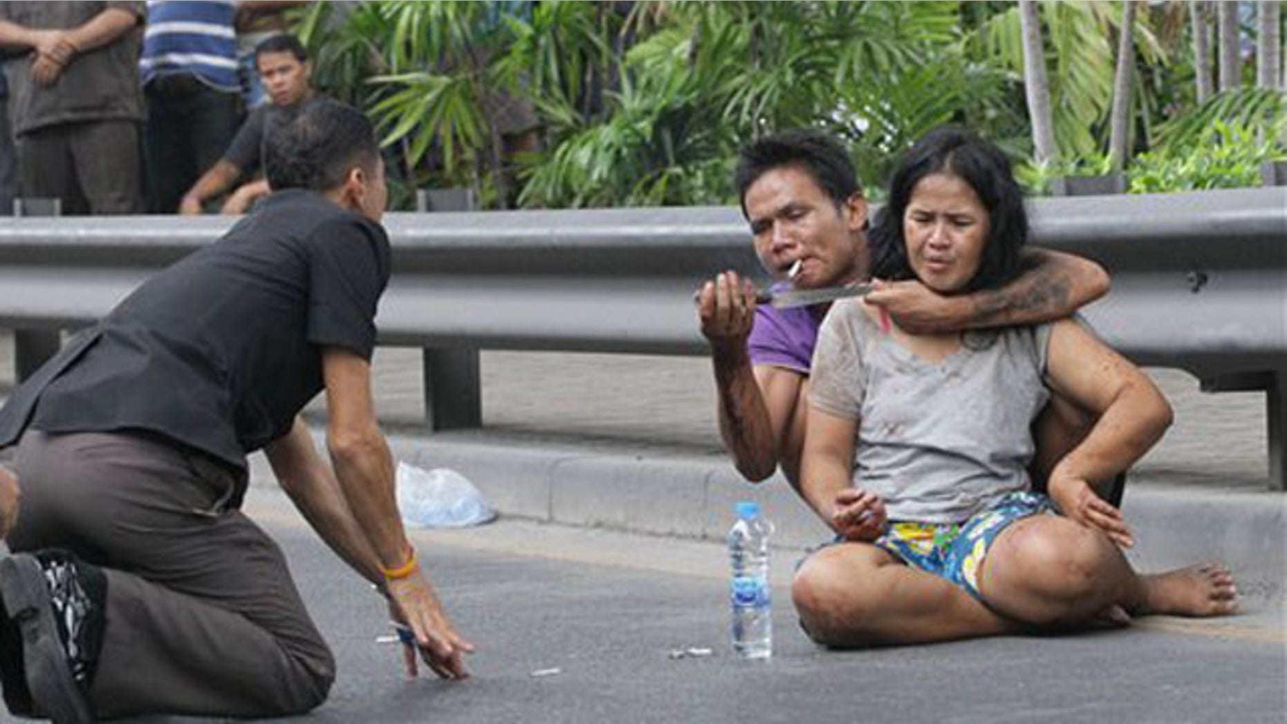 April 5, 2012: A Thai policeman talks to Sakdawut Hamsiri, 30, who holds a knife against his wife Thawee Naiyanit on a street in Bangkok.