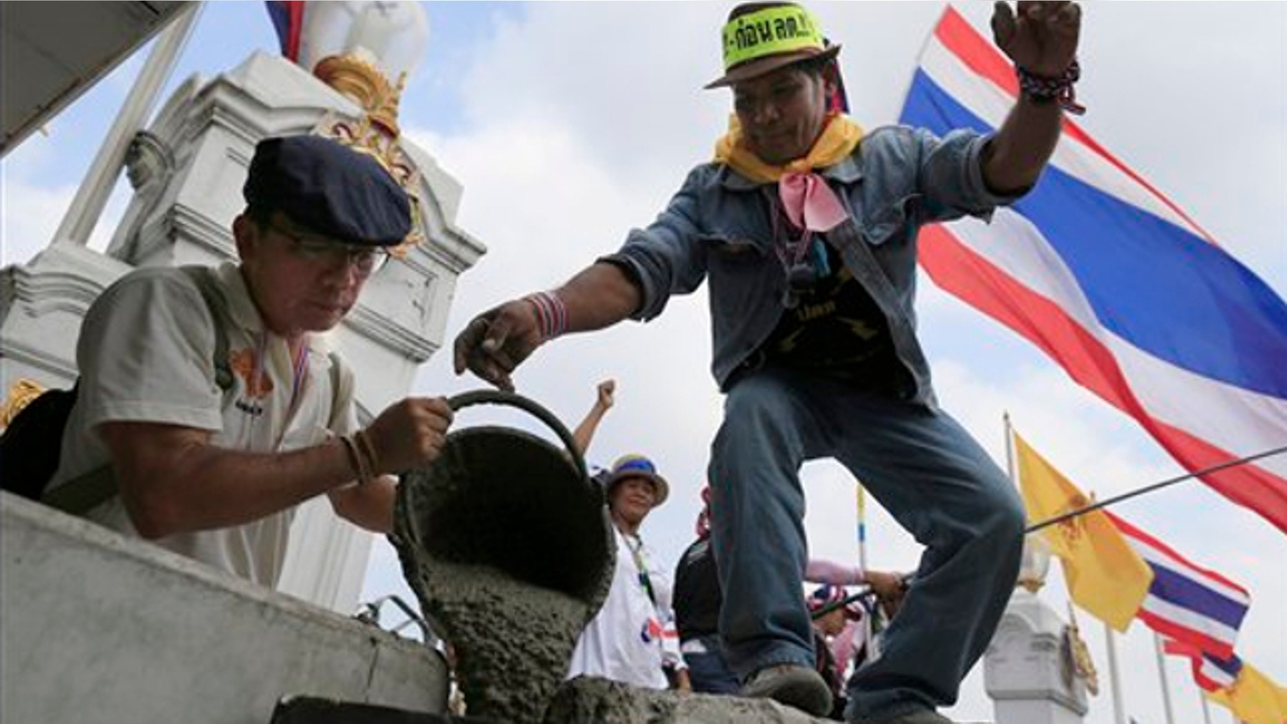 Feb. 17, 2014: Anti-government protesters pour cement on concrete barriers to seal the gate of the prime minister's office of government house during a rally in Bangkok, Thailand.