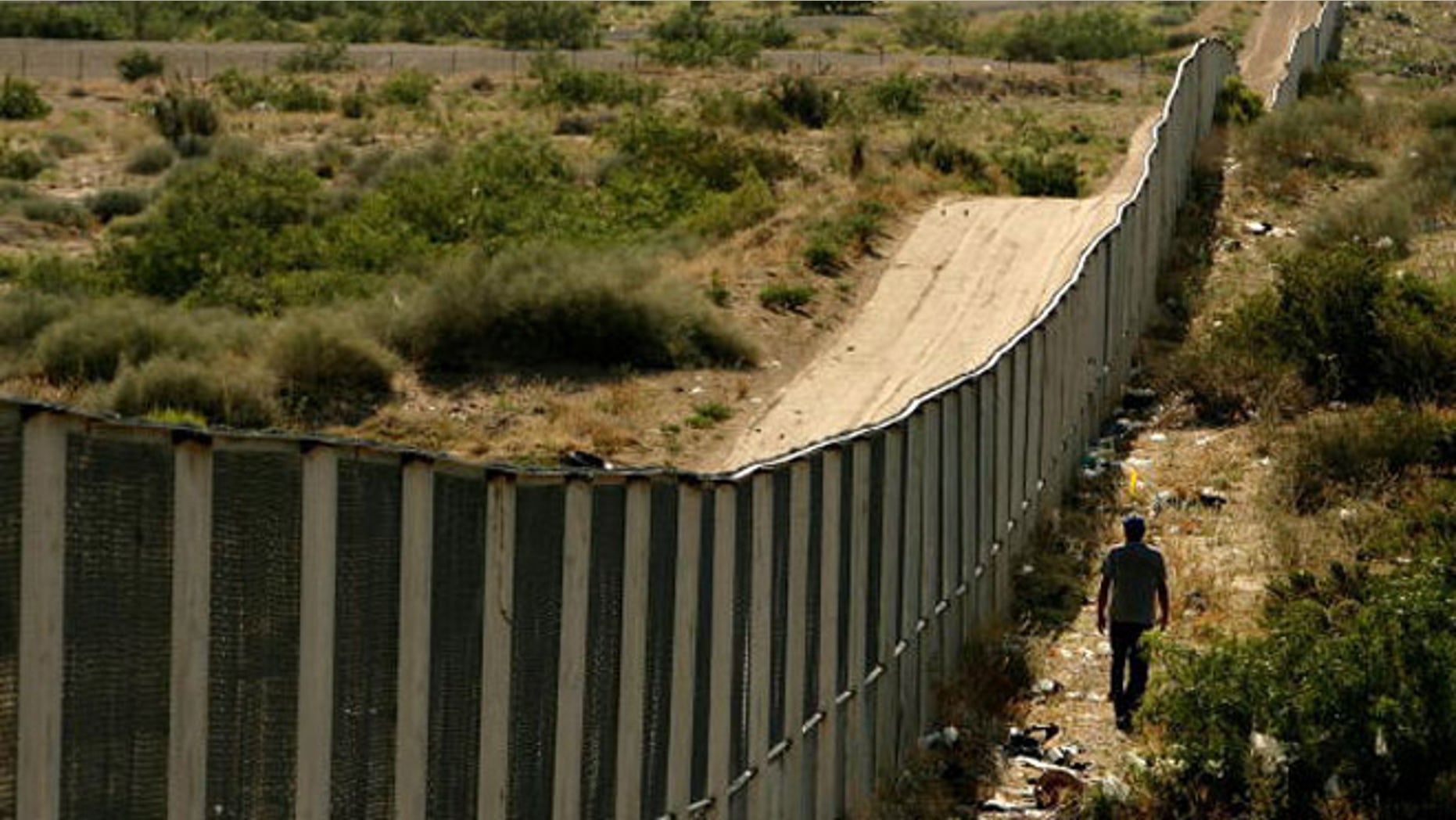 CIUDAD JUAREZ, CHIHUAHUA - JUNE 29: A man walks along the border fence between the U.S. and Mexico on June 29, 2007 in the Anapra area of Ciudad Juarez, Mexico. This area is a popular crossing spot for immigrants to ilegally cross into the United States because houses are close to the border on the south side and the highway is close to the north side. (Photo by Chip Somodevilla/Getty Images)