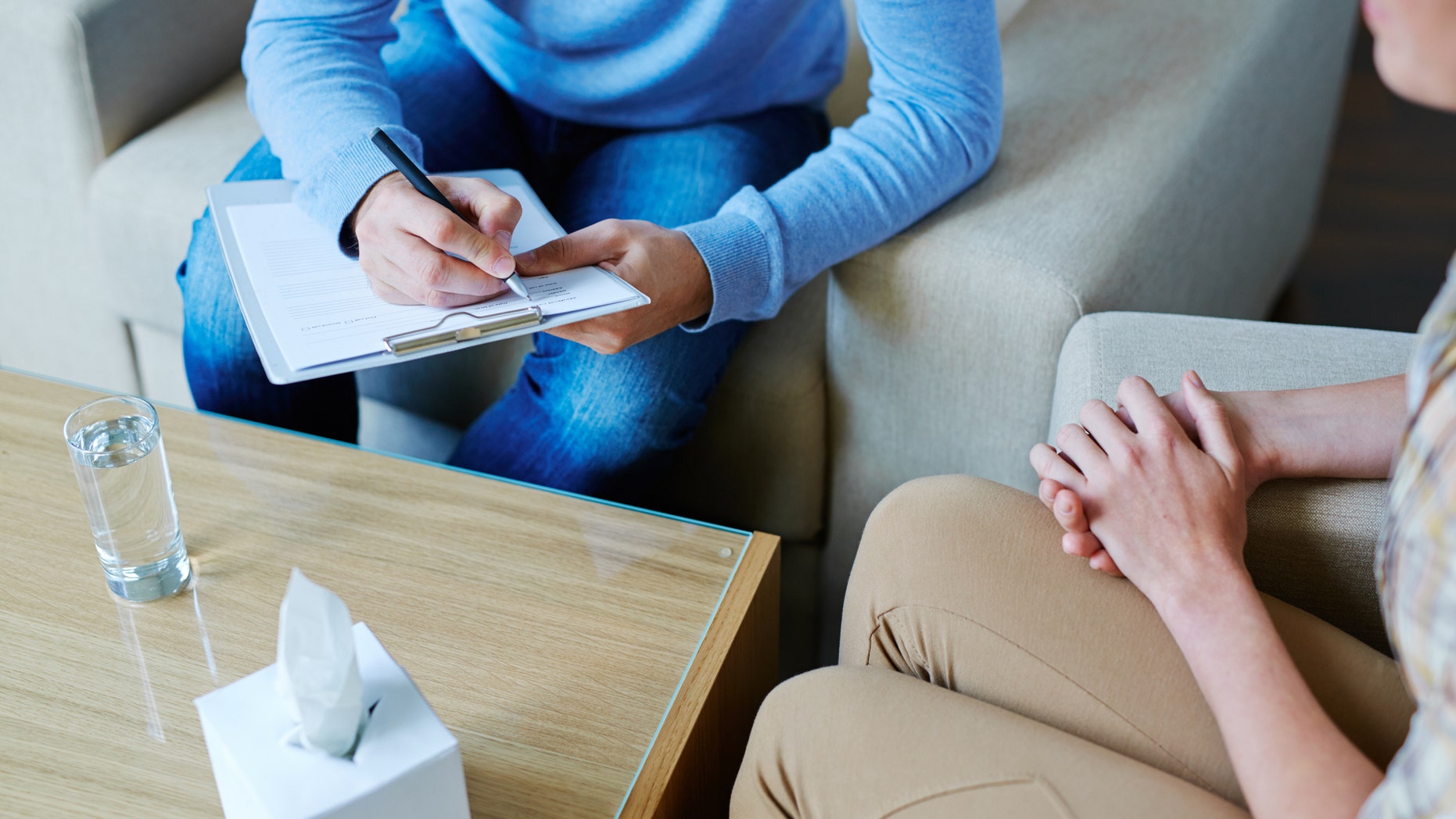 Male psychologist making notes during psychological therapy