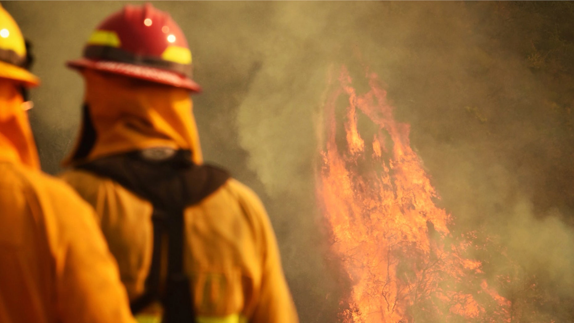 In this photo provided by the Santa Barbara County Fire Department, firefighters keep an eye on flames as pockets of unburned vegetation flare up off Bella Vista Dr. in Montecito, Calif., Wednesday, Dec. 13, 2017.