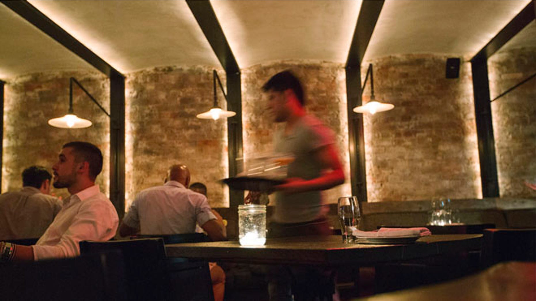 June 12, 2013: A server clears dishes from a table inside a New York restaurant.