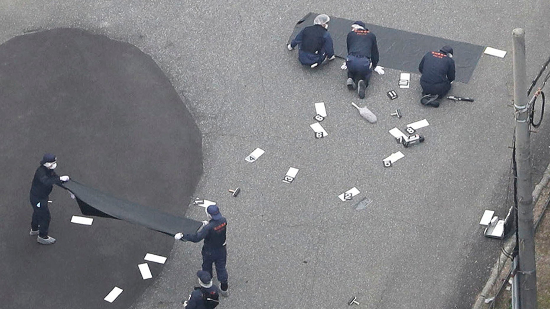 June 26, 2018: Investigators work at an elementary school after a man fatally shot a security guard, in Toyama, northwest of Tokyo.