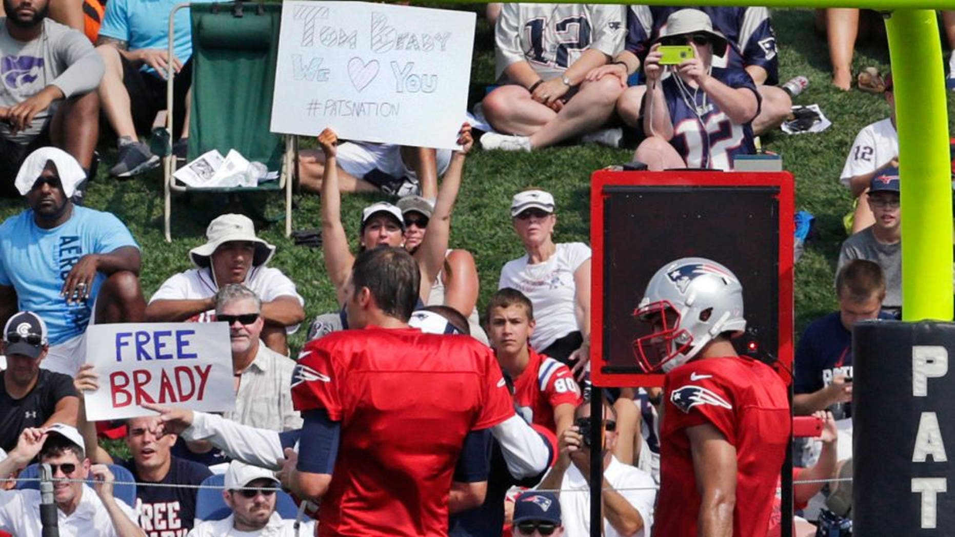 A fan holds a sign reading "Free Brady" as New England Patriots quarterback Tom Brady, left, prepares to practice with his back-up Jimmy Garoppolo during an NFL football training camp in Foxborough, Mass., Thursday, July 30, 2015. (AP Photo/Charles Krupa)