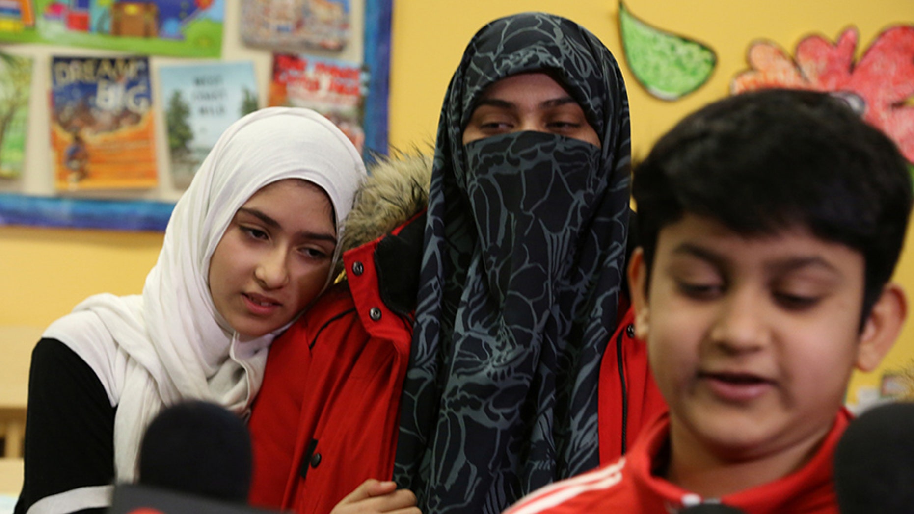 Khawlah Noman, 11, embraces her mother, Saima Samad, as her brother Mohammed Zakariyya, 10, speaks to reporters.
