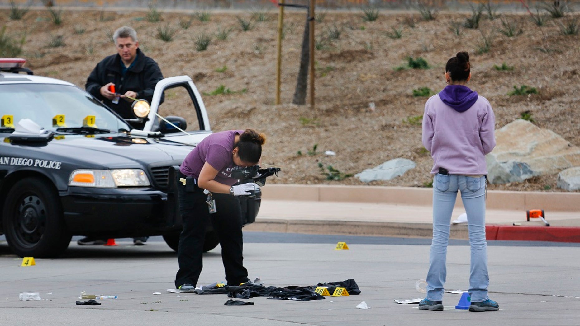 San Diego police investigate the scene of an early Saturday morning shooting. Police say a 15-year-old boy left behind a suicide note before he was killed by police officers after pointing a BB gun at them in a high school parking lot in the dark.