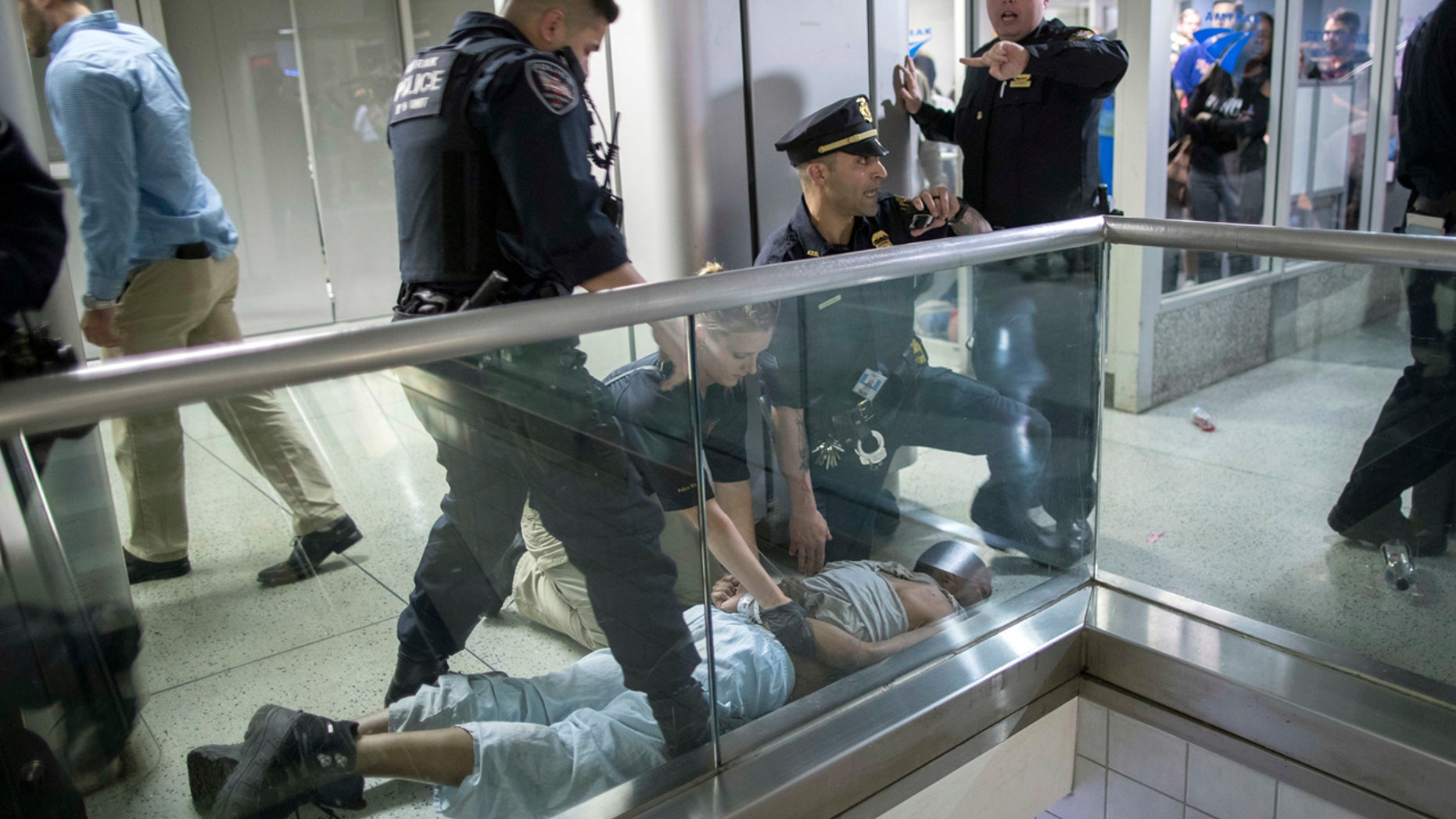 New York City police officers detain a passenger from a disabled New Jersey Transit train who became belligerent and sparked a stampede among passengers leaving the overcrowded station once the train finally arrived at New York's Penn Station, Friday, April 14, 2017.