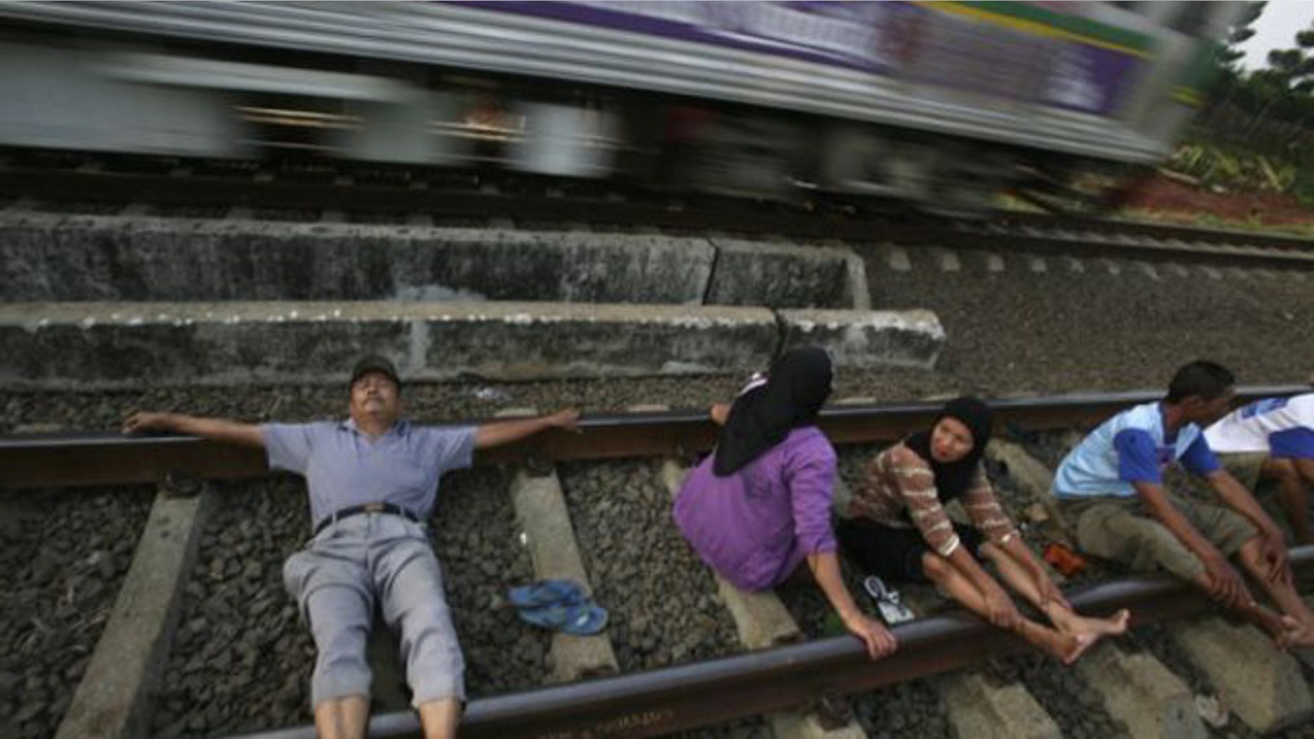 In this July 26, 2011 photo, villagers lie on a railway track for an electricity therapy in Rawa Buaya, Jakarta, Indonesia. People in the outskirt of the capital have been participating in the treatment believing that the the electricity current from the track could cure various diseases.