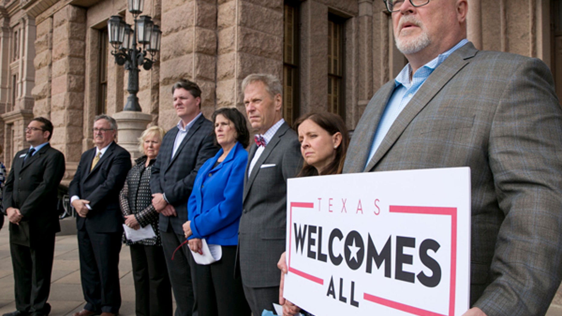 Brad Kent, chief sales and services officer for Visit Dallas, holds a sign at a news conference in Austin, Texas