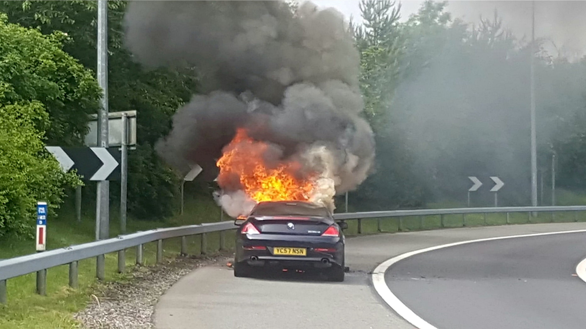 Andrew Lindsay's BMW bursting into flames. A DAD-of-oneâs BMW 6 Series erupted in a fireball on a motorway and trapped him inside the burning car â when the locks jammed. See NTI story NTIBMW. Andrew Lindsay, 45, desperately tried to escape the motor when it burst into flames while he was travelling at 70mph on the M6 Toll Road. He managed to shoulder barge the driverâs door open and leap from the car moments before the engine exploded and melted the tyres to the road. Andrew, a copy editor from Whittington, Staffs., was on his way to see family in North Wales when the blaze broke out on June 1.
