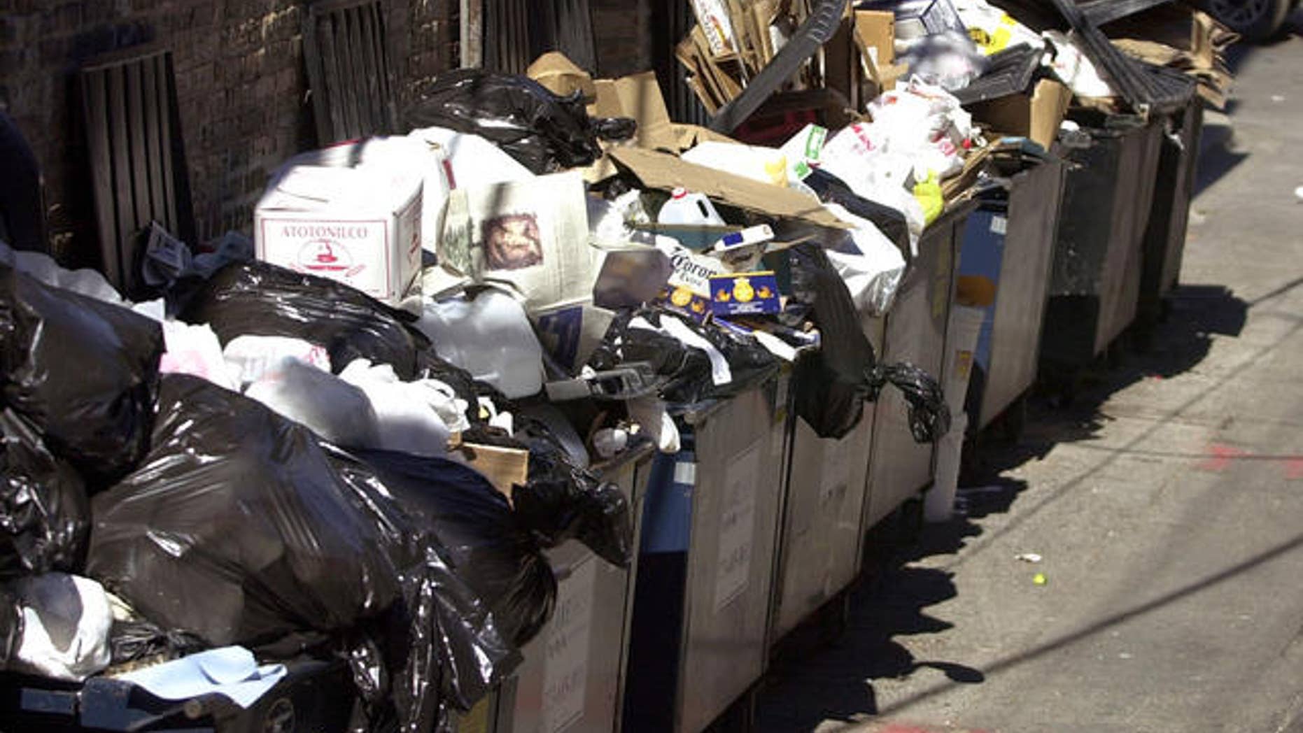 Trash overflows from dumpsters behind an apartment building. (AP)