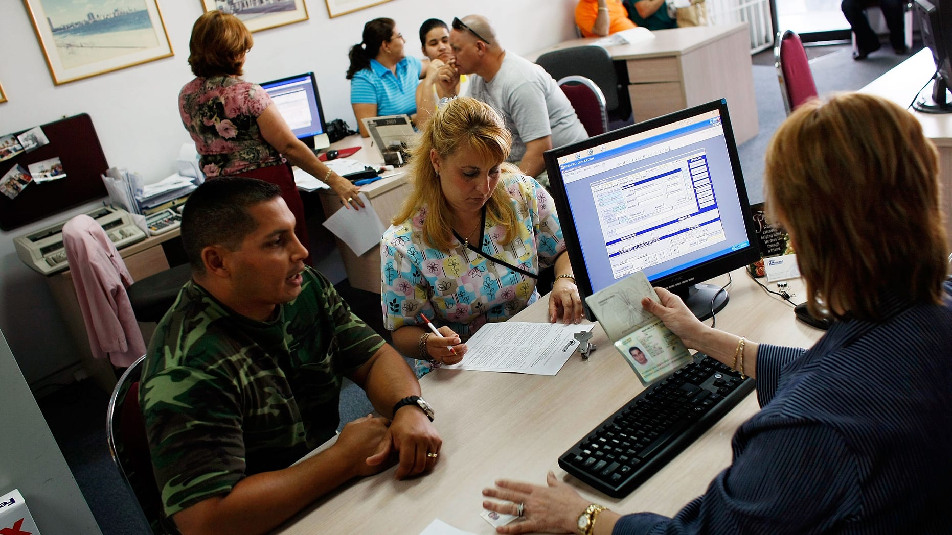 MIAMI - APRIL 13: Omar Garcia (L) and Giselle Bordin purchase tickets to Cuba from travel agent Marizela Somosa in the offices of Marazul Charters on April 13, 2009 in Miami, Florida. Today, U.S. President Barack Obama loosened travel restrictions for Cuban Americans traveling to Cuba as well as money transfers to the island. (Photo by Joe Raedle/Getty Images)