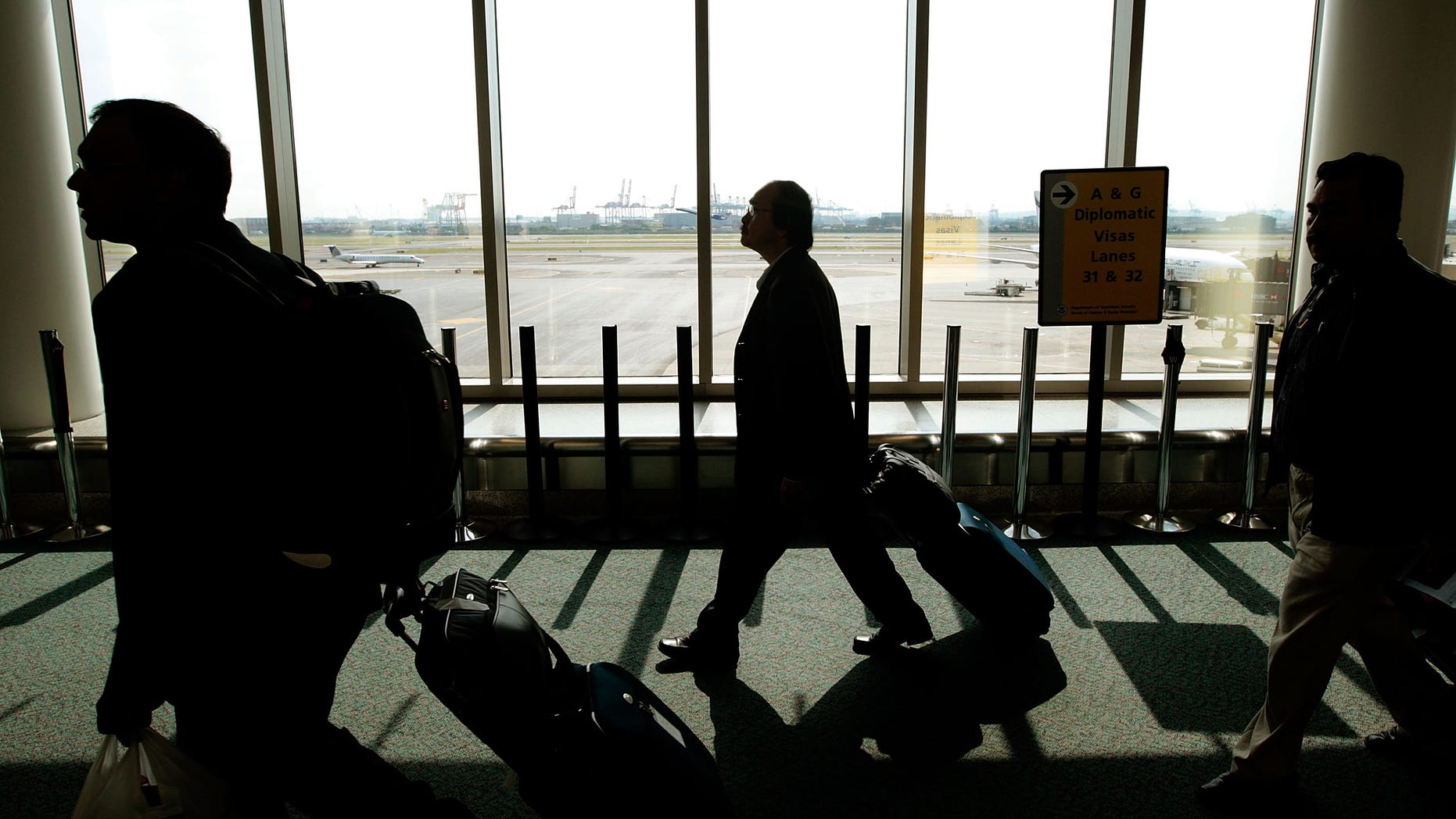 NEWARK, NJ - AUGUST 24: Travelers with bags walk toward the passport control line upon arriving to Newark International Airport August 24, 2009 in Newark, New Jersey. Officials with U.S. Customs and Border Protection are introducing are introducing the Global Entry program, which allows pre-screening and approval of travelers and faster trips through customs and passport lines upon arriving into the United States. (Photo by Chris Hondros/Getty Images)