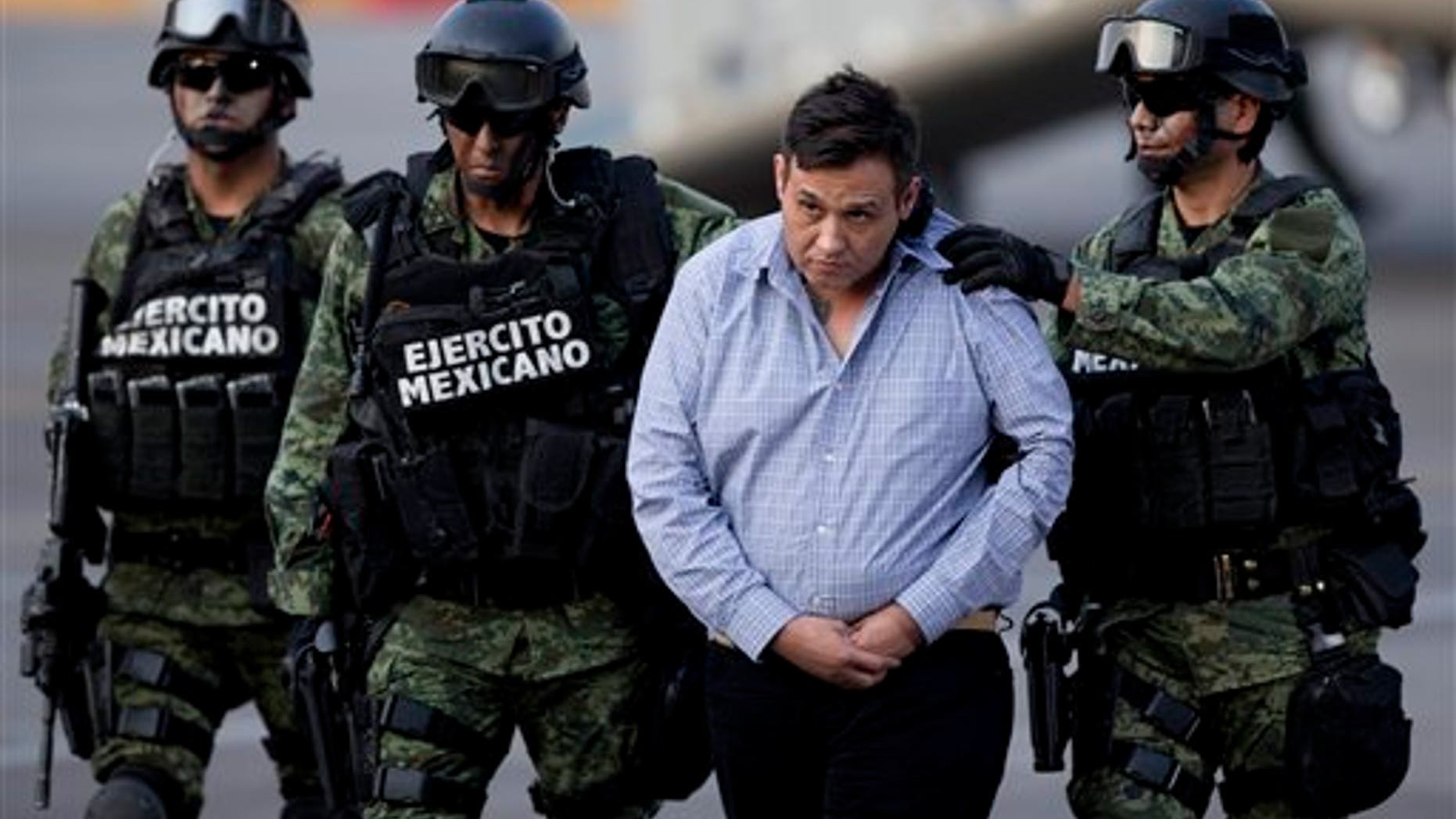 Soldiers escort a man who authorities identified as Omar Trevino Morales, alias "Z-42," leader of the Zetas drug cartel, as he is moved from a military plane to a military vehicle at the Attorney General's Office hangar in Mexico City, Wednesday, March 4, 2015. An official who was not authorized to be quoted by name because of government policy, said Morales was arrested on Wednesday in a pre-dawn raid in San Pedro Garza Garcia, a wealthy suburb of the northern city of Monterrey. (AP Photo/Eduardo Verdugo)