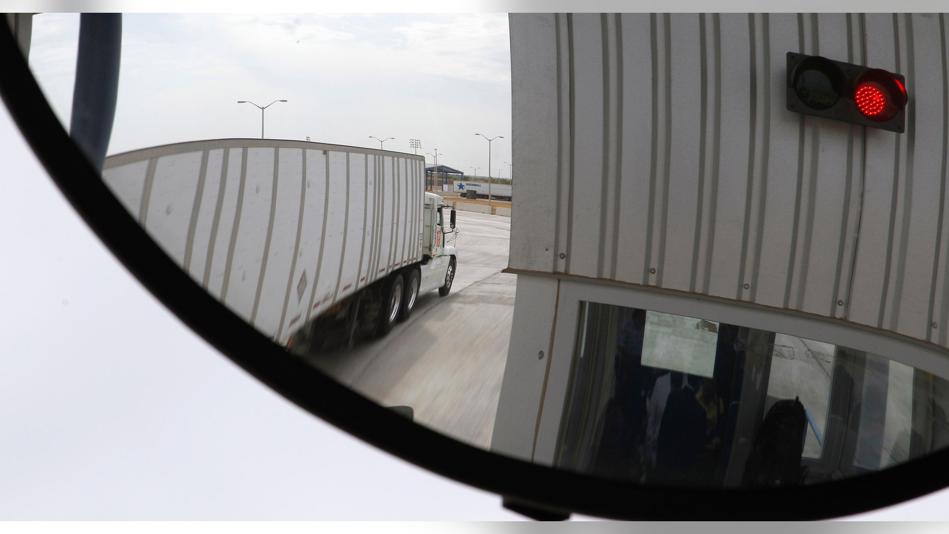 In this May 6, 2011 file photo, a trucker, seen in a security mirror, passes through an inspection booth for commercial traffic heading north into the U.S. from Mexico at the World Trade Bridge in Laredo, Texas.