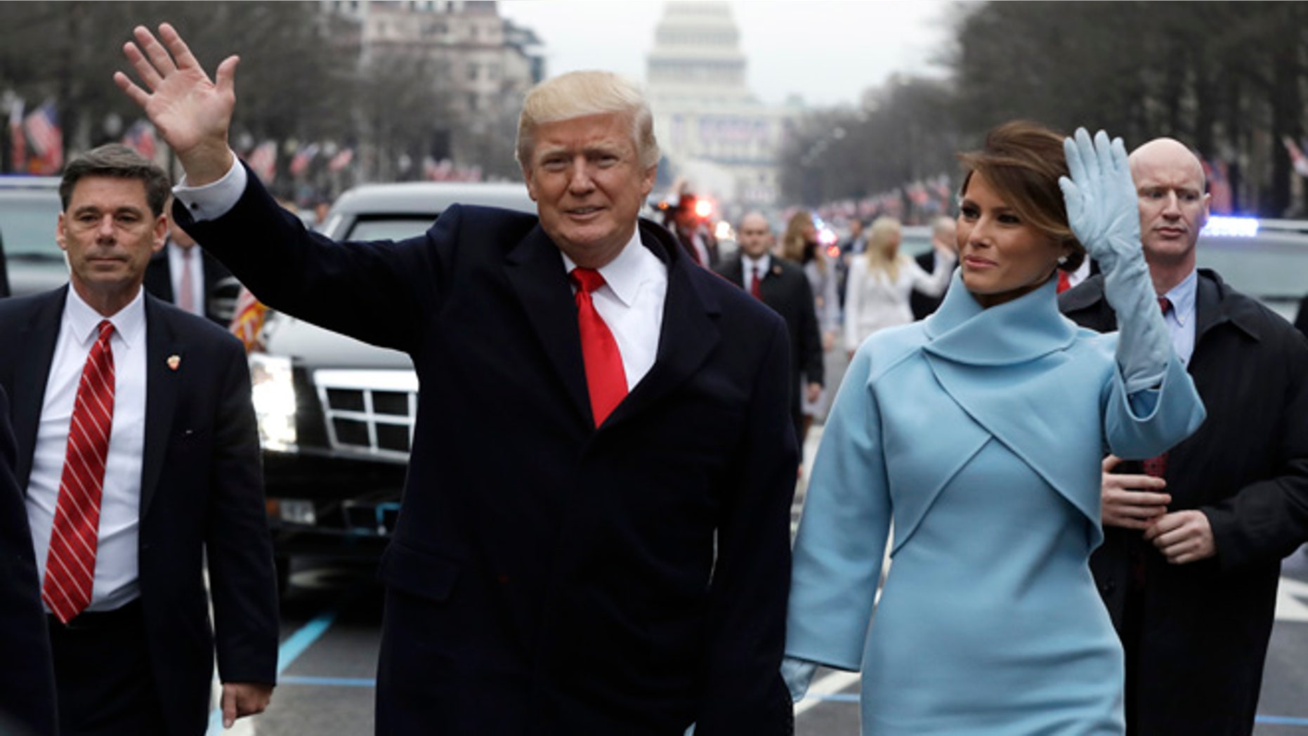 President Donald Trump waves as he walks with first lady Melania Trump during the inauguration parade on Pennsylvania Avenue in Washington, Friday, Jan. 20, 2016. (AP Photo/Evan Vucci, Pool)