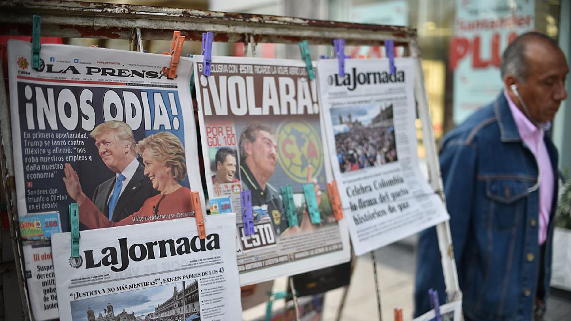 A man walks by a newsstand displaying front pages showing images of US presidential candidates debate and Colombia's peace agreement, in Mexico City on September 27, 2016. (Photo credit: YURI CORTEZ/AFP/Getty Images)
