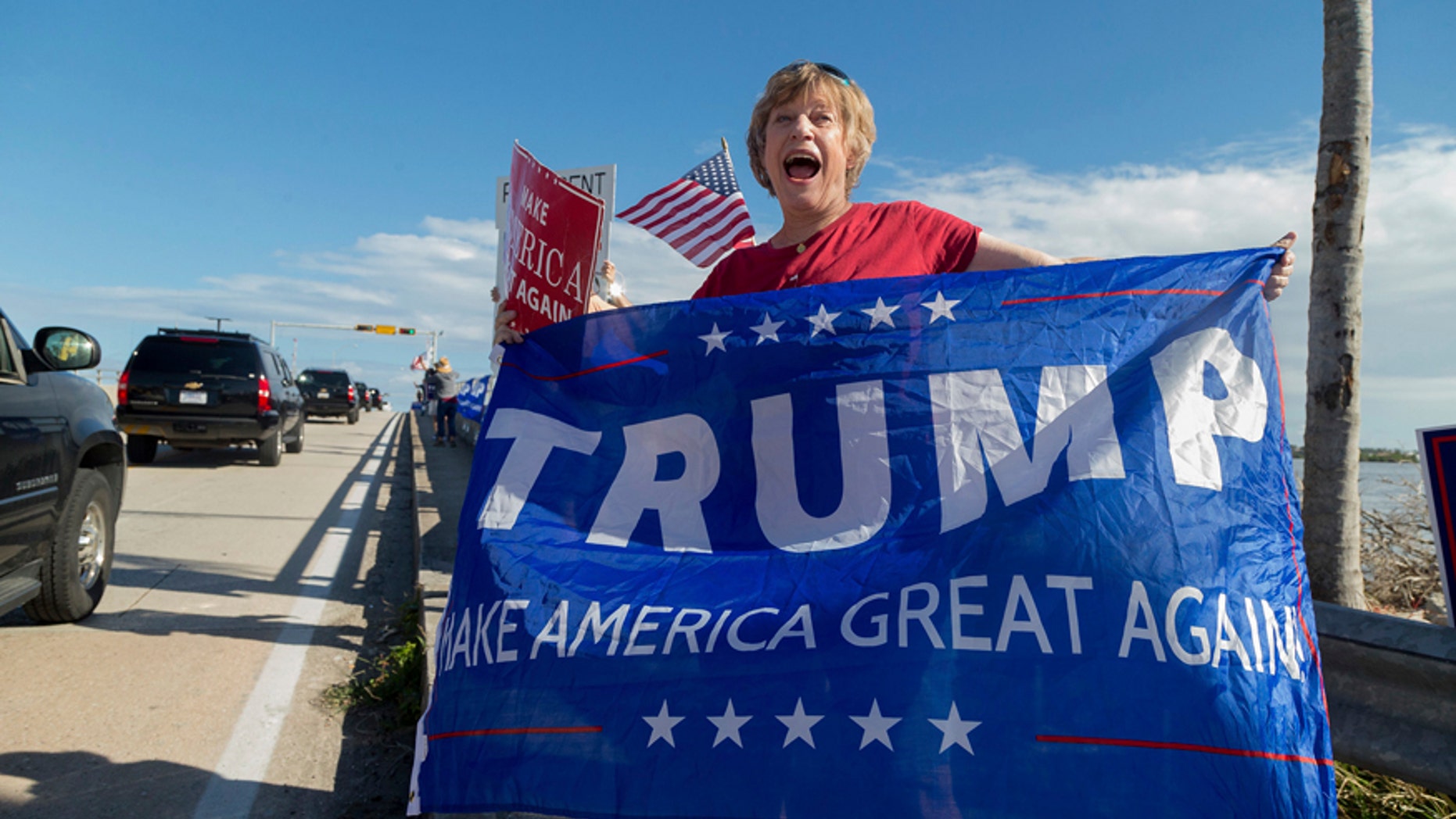 Mary Jude Smith cheers for President Donald Trump as his motorcade passes by on Southern Blvd. enroute to his Mar-a-Lago estate from Trump International Golf Club, Thursday, Dec. 28, 2017, in West Palm Beach, Fla. (Greg Lovett/Palm Beach Post via AP)