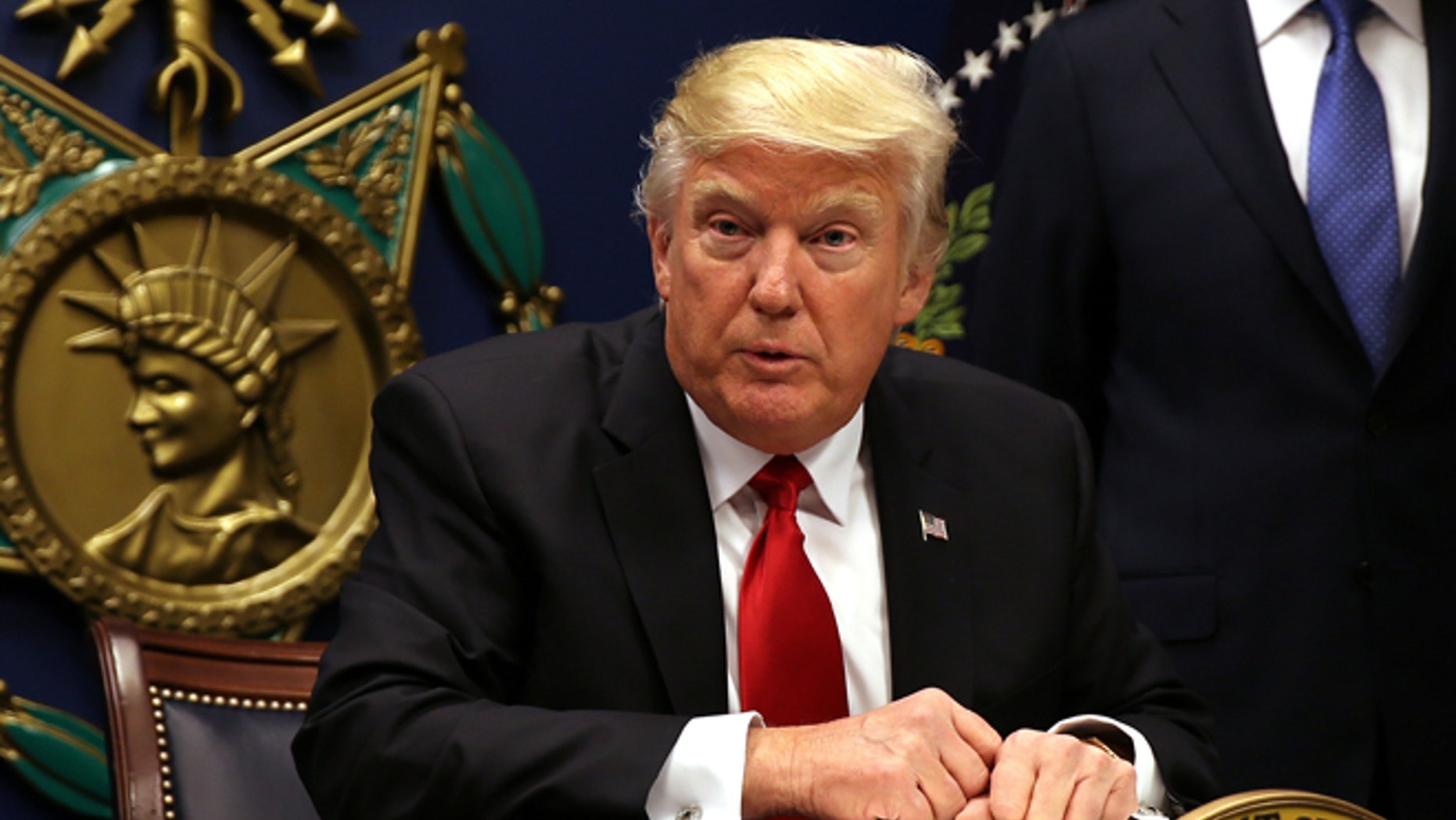 U.S. President Donald Trump signs an executive order to impose tighter vetting of travelers entering the United States, at the Pentagon in Washington, U.S., January 27, 2017. The executive order signed by Trump imposes a four-month travel ban on refugees entering the United States and a 90-day hold on travelers from Syria, Iran and five other Muslim-majority countries. Picture taken January 27, 2017. REUTERS/Carlos Barria - RTSXWM6