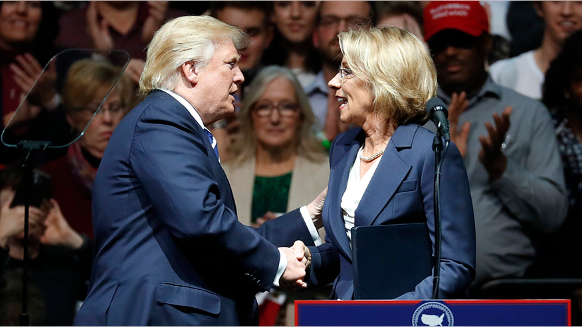 President-elect Donald Trump shakes hands with his pick for Education Secretary Betsy DeVos during a rally, in Grand Rapids, Mich., Friday, Dec. 9, 2016.
