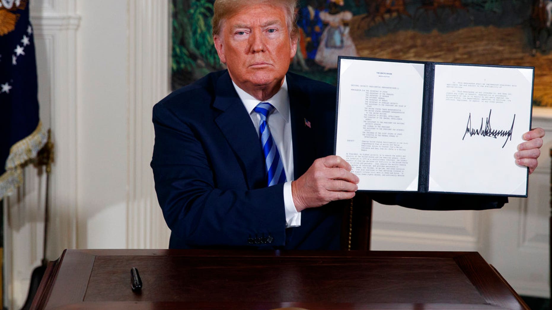 President Donald Trump shows a signed Presidential Memorandum after delivering a statement on the Iran nuclear deal from the Diplomatic Reception Room of the White House, Tuesday, May 8, 2018, in Washington. (AP Photo/Evan Vucci)