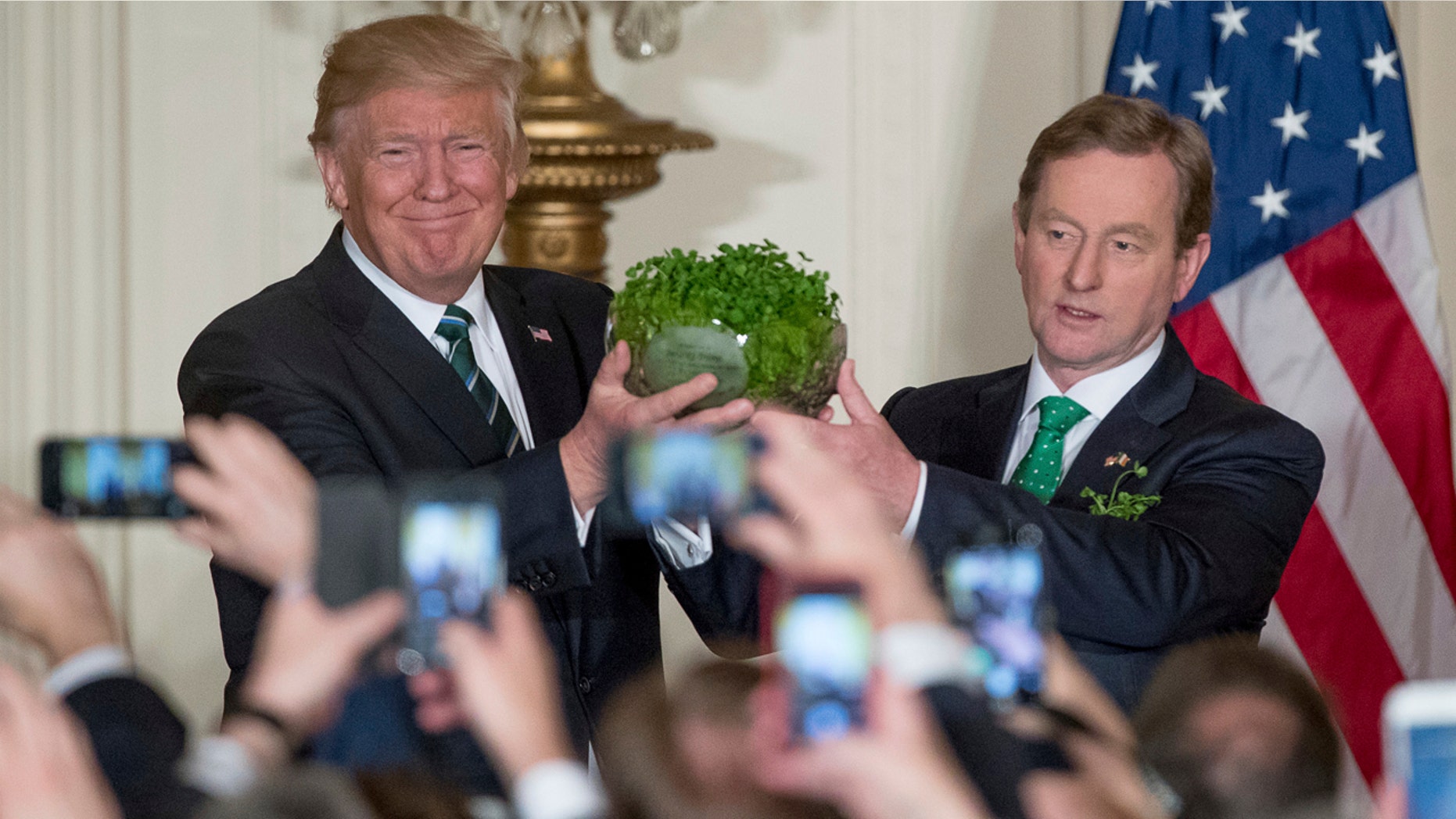 President Donald Trump, left, and Irish Prime Minister Enda Kenny, right, hold up a bowl of Irish shamrocks during a St. Patrick's Day reception in the East Room of the White House in Washington, Thursday, March 16, 2017. (AP Photo/Andrew Harnik)