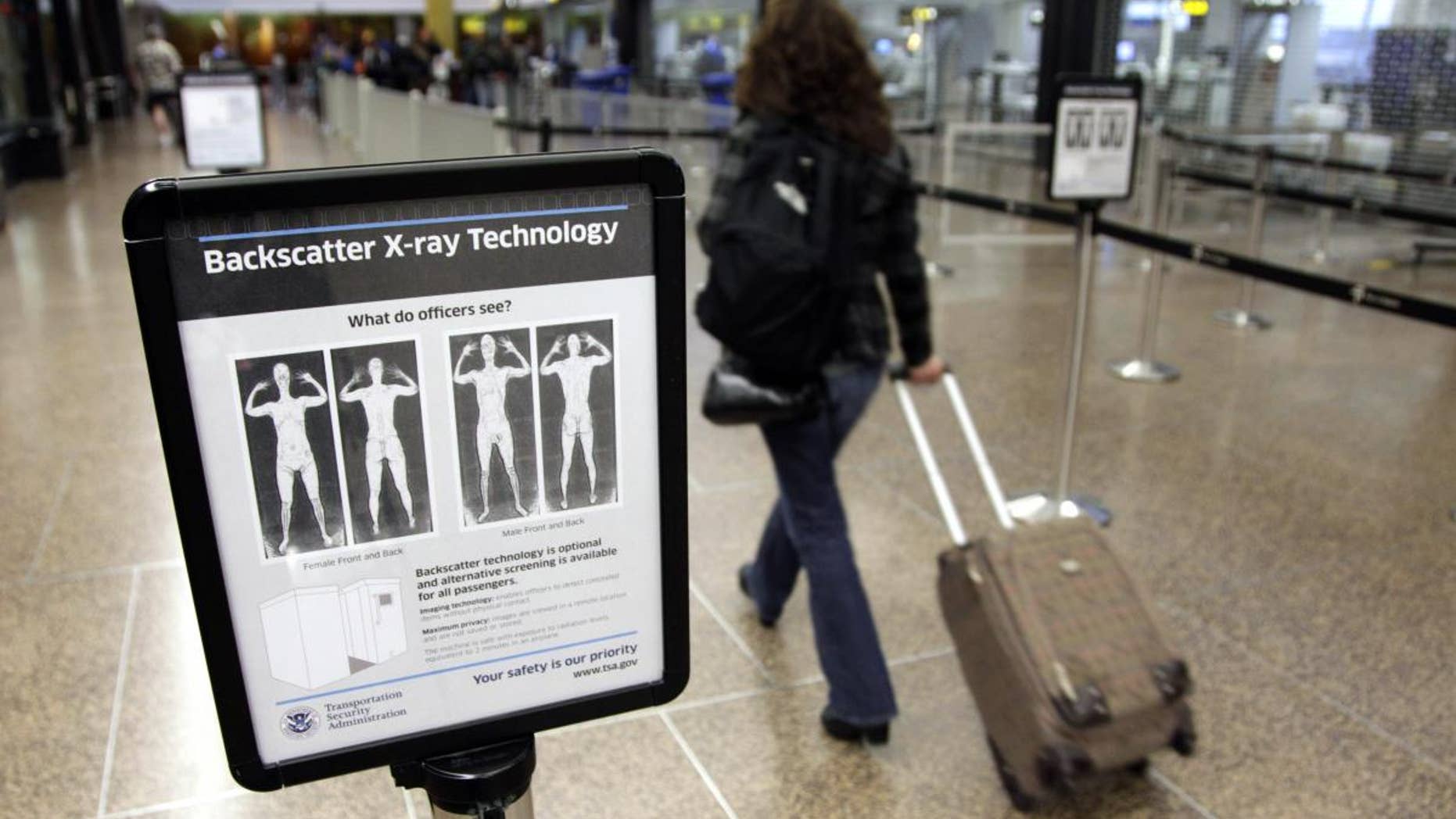 In this Nov. 19, 2010 file photo, a passenger walks past a sign informing travelers about the use of full-body scanners for TSA security screening at Seattle-Tacoma International Airport in Seattle. (AP Photo/Ted S. Warren, File)
