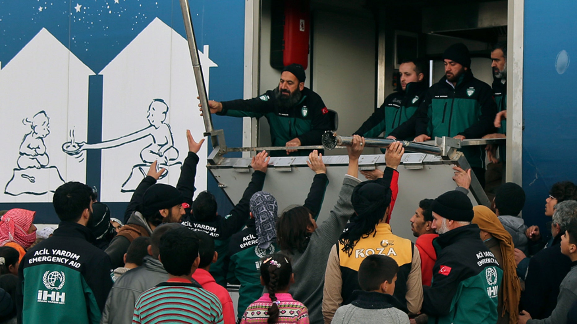Feb. 7, 2016: In this photo provided by Turkish Islamic aid group IHH, Syrians gather to collect food from the group workers at a temporary refugee camp for displaced Syrians in northern Syria, near Bab al-Salameh border crossing with Turkey.