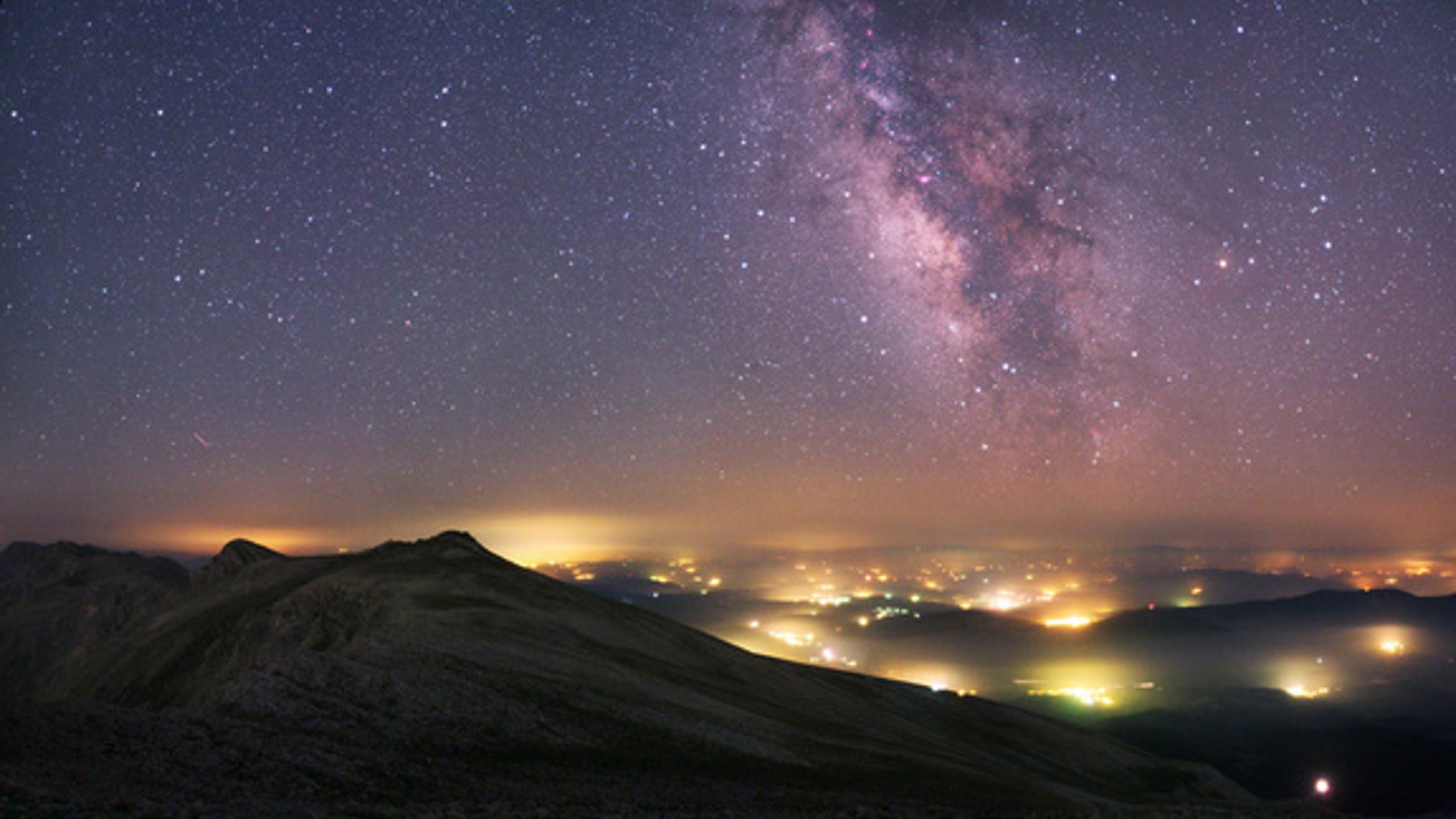 A view from the Uludag National Park in Turkey. The Milky Way stretches across the sky above the manmade pockets of hazy lights from the towns and villages below.