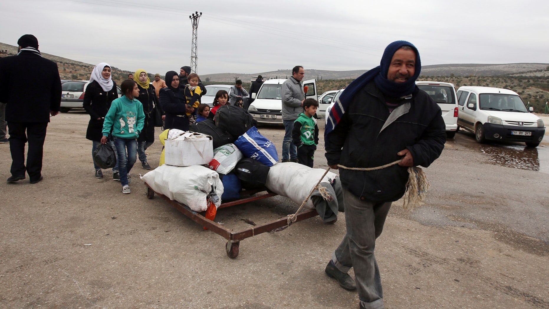 A Syrian man pulls their belongings after he was evacuated with his family from Aleppo, near Idlib, Syria, Friday, Dec. 16, 2016.