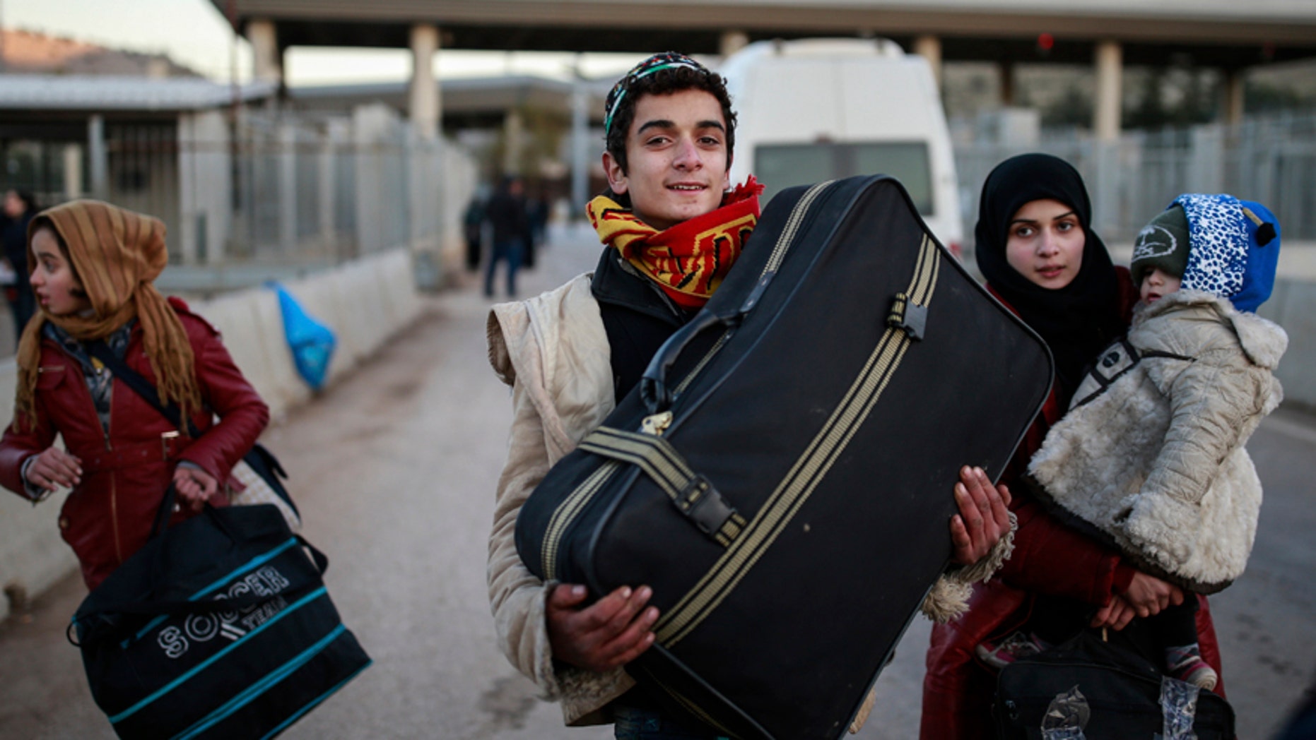 Members of a Syrian family carry their belongings after they crossed into Turkey at the Cilvegozu border gate with Syria, near Hatay, southeastern Turkey, Sunday, Dec, 18, 2016. Several people were able to cross into Turkey after they managed to leave the embattled Syrian city during the ceasefire, and arrived to Turkey by their own means. The Aleppo evacuation was suspended Friday after a report of shooting at a crossing point into the enclave by both sides of the conflict. (AP Photo/Emrah Gurel)